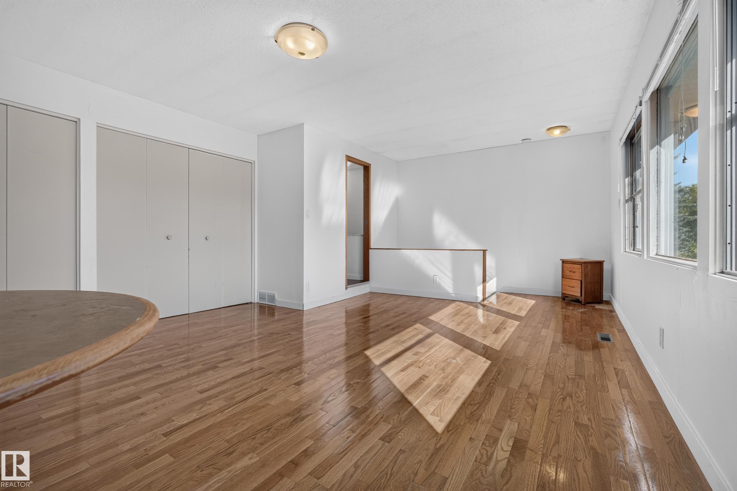 Hardwood flooring, multiple windows, two flush-mount lighting fixtures, and a half-height wall - 11603 72 Avenue Nw, Edmonton, AB