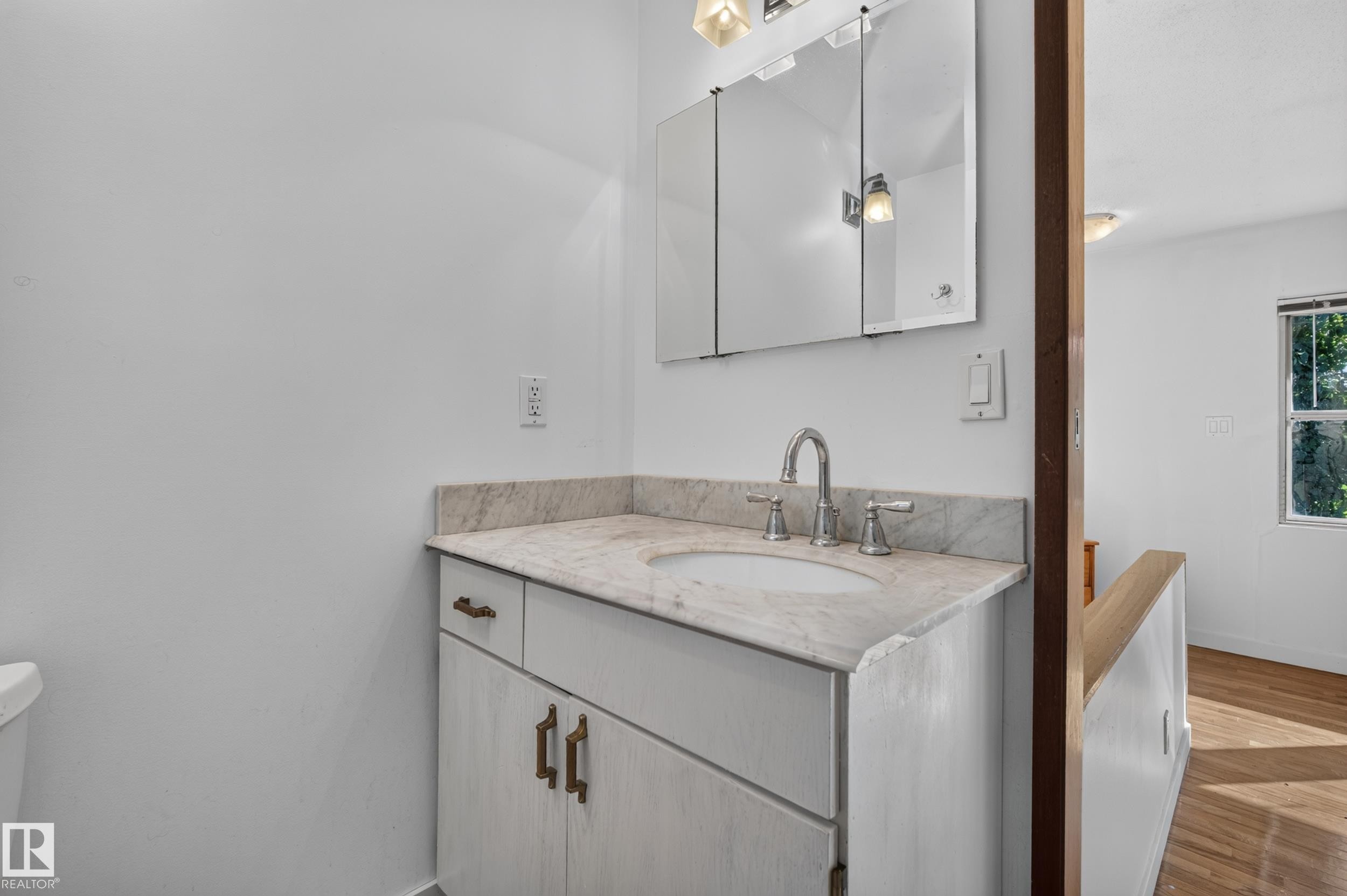 White vanity with a neutral-toned countertop, undermount sink, and polished chrome faucet - 11603 72 Avenue Nw, Edmonton, AB