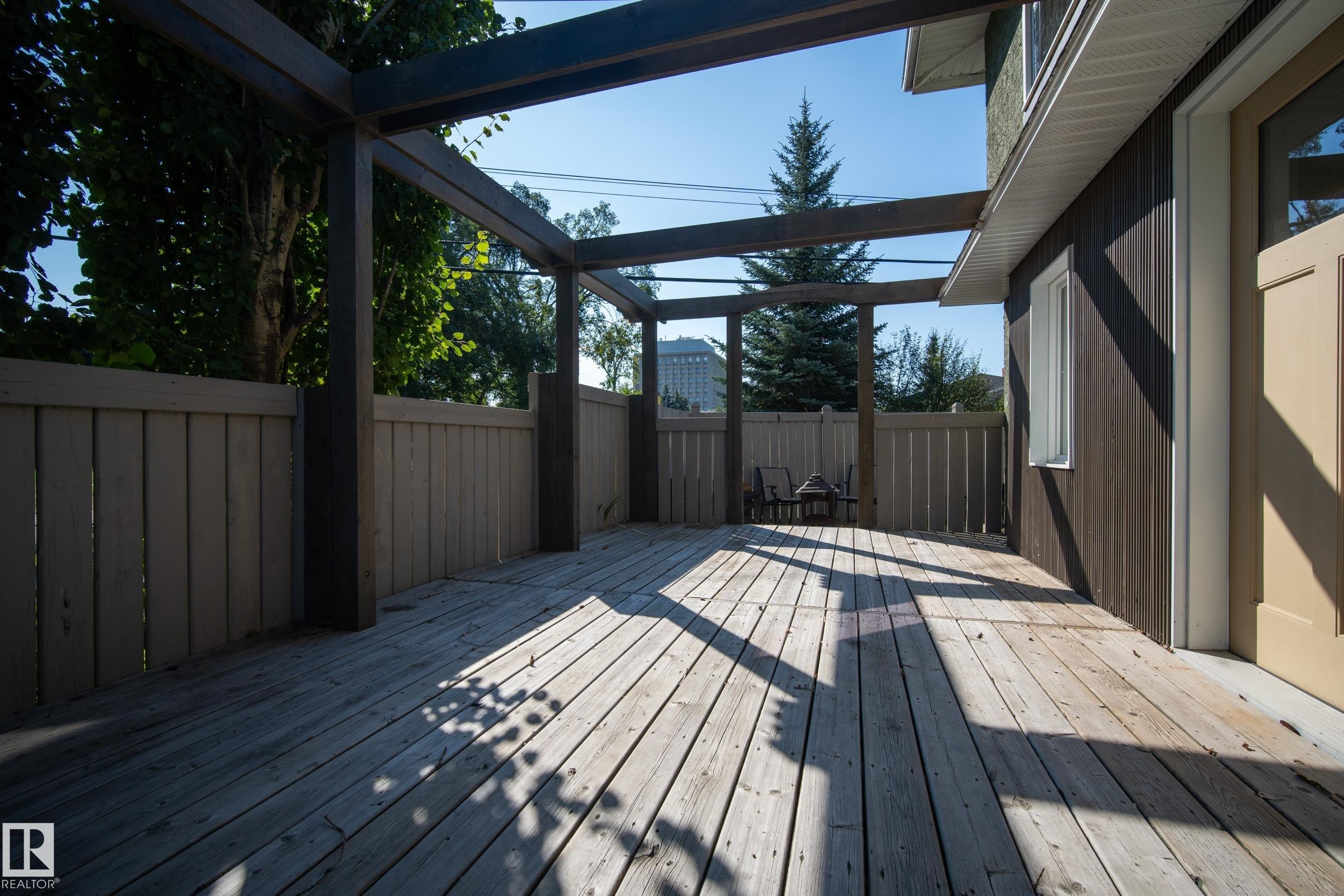 Expansive wood-finish decking with a privacy fence, an overhead trellis structure, and direct exterior access - 11603 72 Avenue Nw, Edmonton, AB