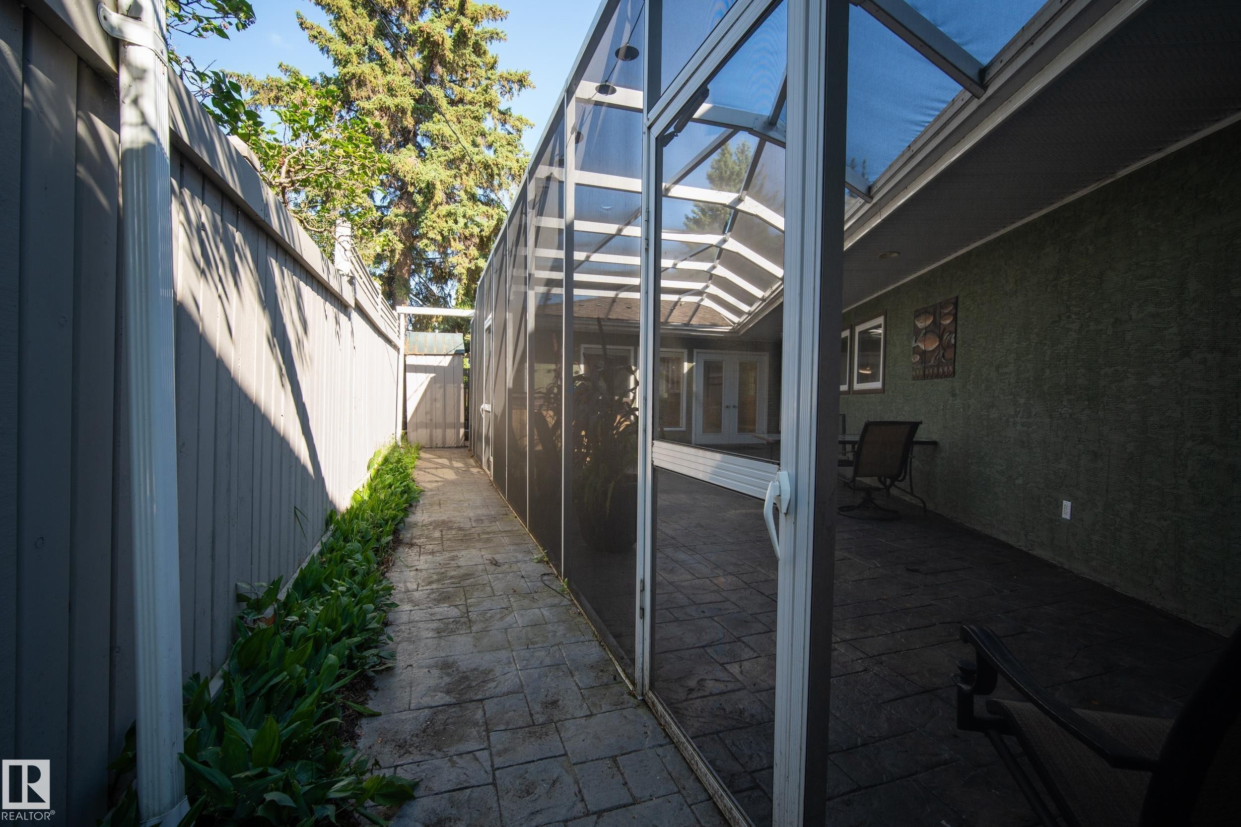 Enclosed patio with a screen enclosure, stamped concrete flooring, and an exterior green textured wall - 11603 72 Avenue Nw, Edmonton, AB