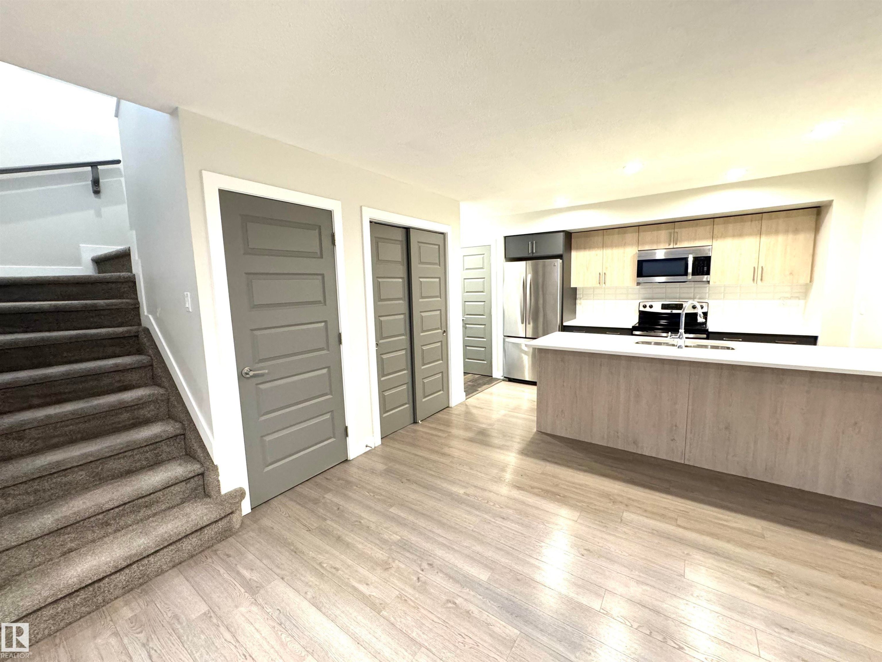 Kitchen featuring stainless steel appliances, light wood-finish cabinetry, and a white countertop island - 12046 89 Street Nw, Edmonton, AB