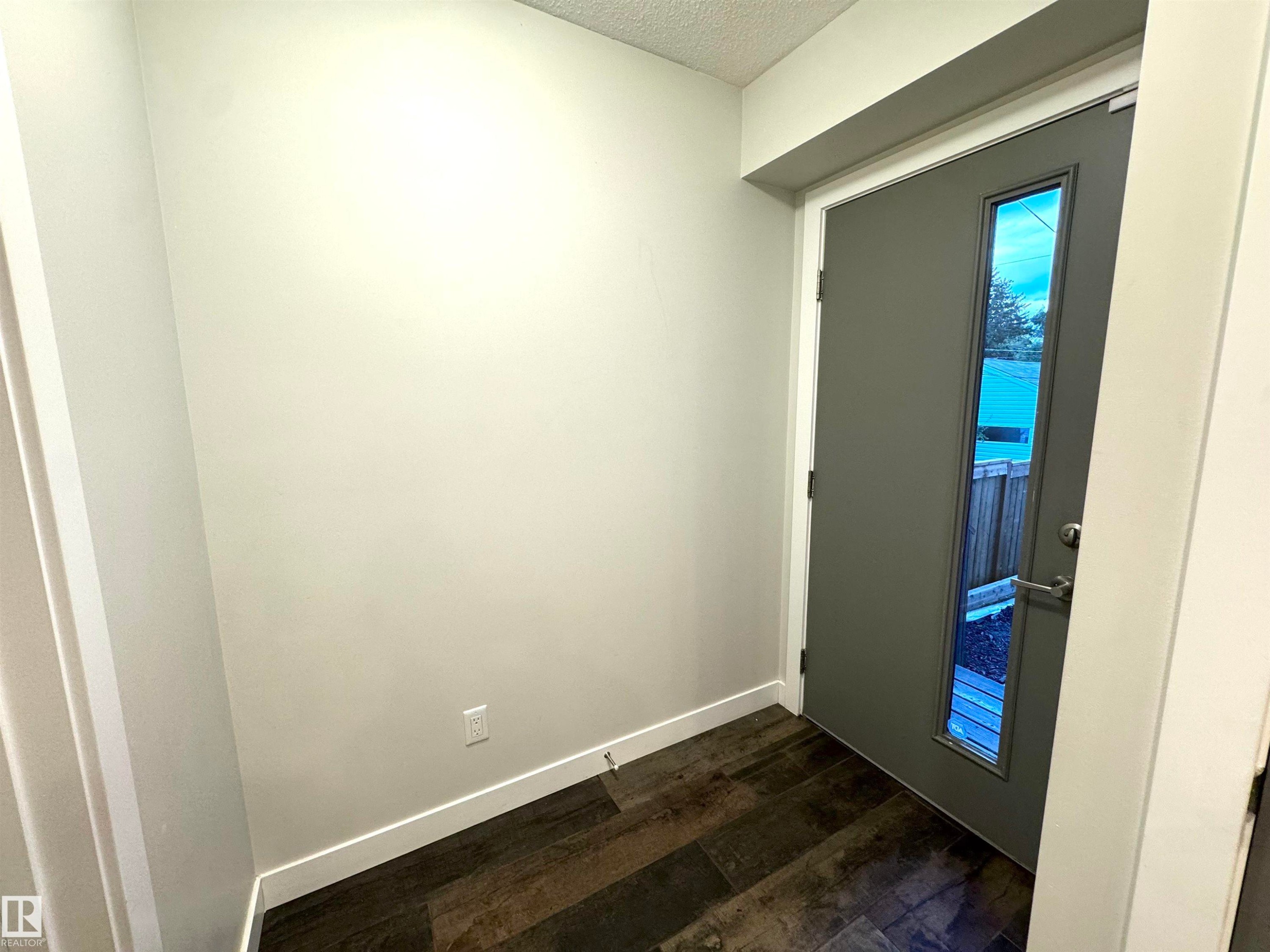 Entryway featuring a contemporary door with a vertical glass insert, dark wood-finish flooring, and light-toned walls - 12046 89 Street Nw, Edmonton, AB