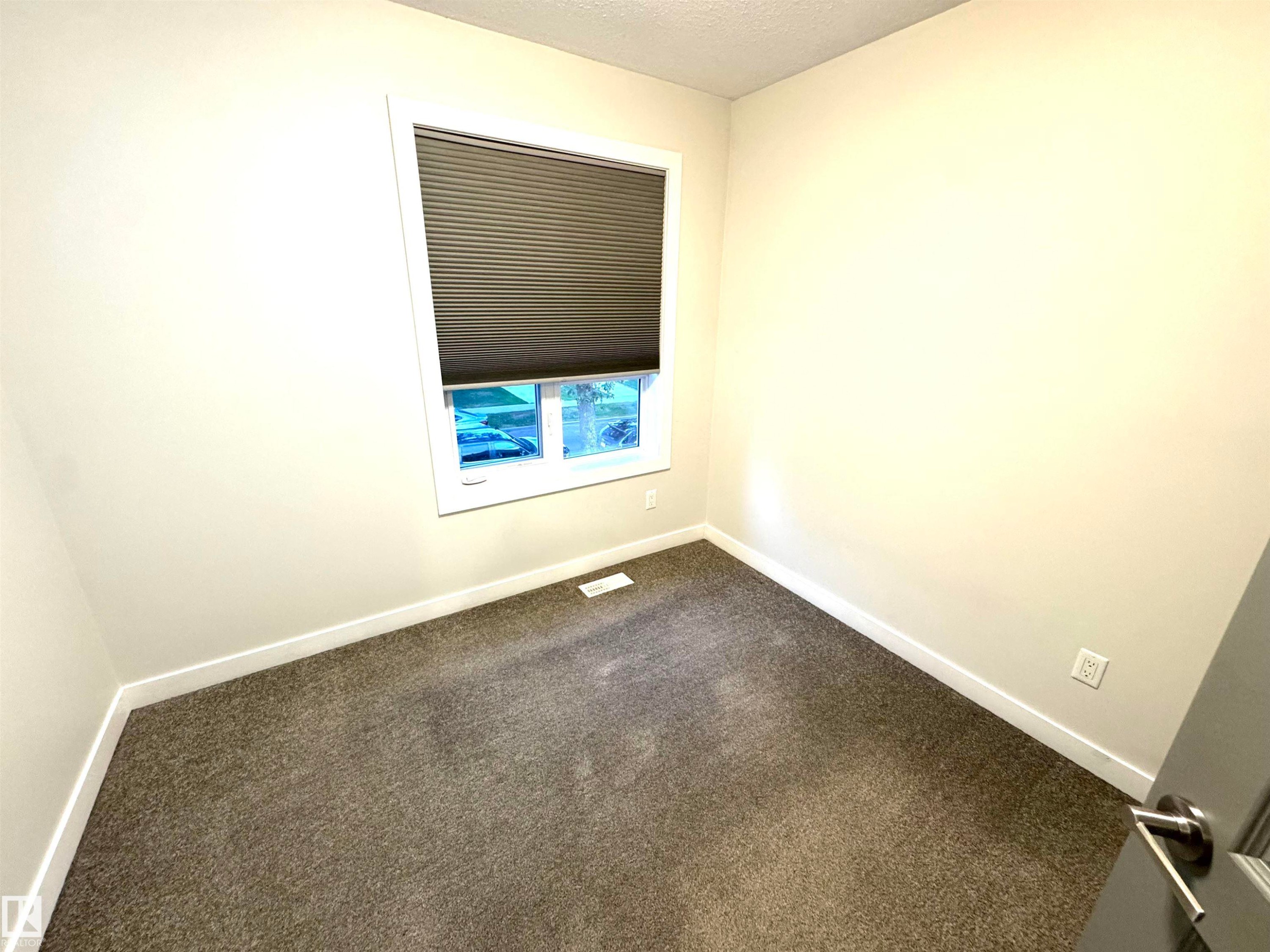 Neutral wall finishes with a single window featuring horizontal blinds - 12046 89 Street Nw, Edmonton, AB