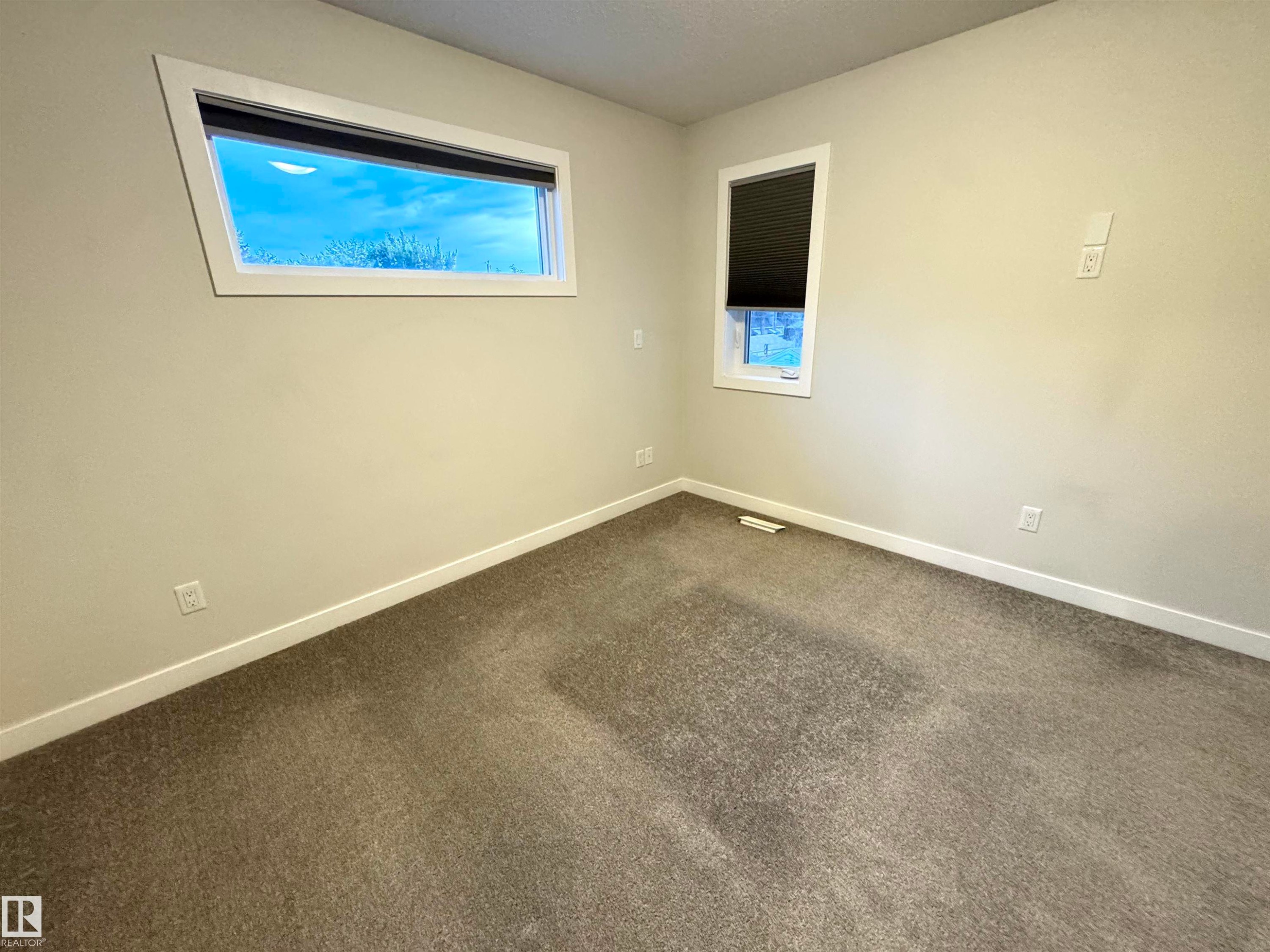 Neutral wall paint, carpeted flooring, and two windows providing natural illumination - 12046 89 Street Nw, Edmonton, AB