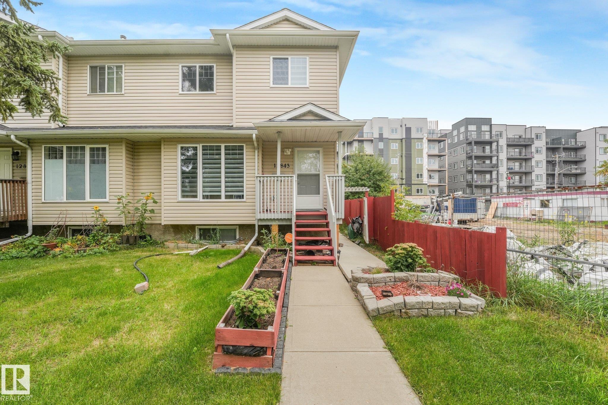 Two-story residence featuring light-toned siding, a front porch with railing, and a concrete walkway - 12843 67 Street Nw, Edmonton, AB