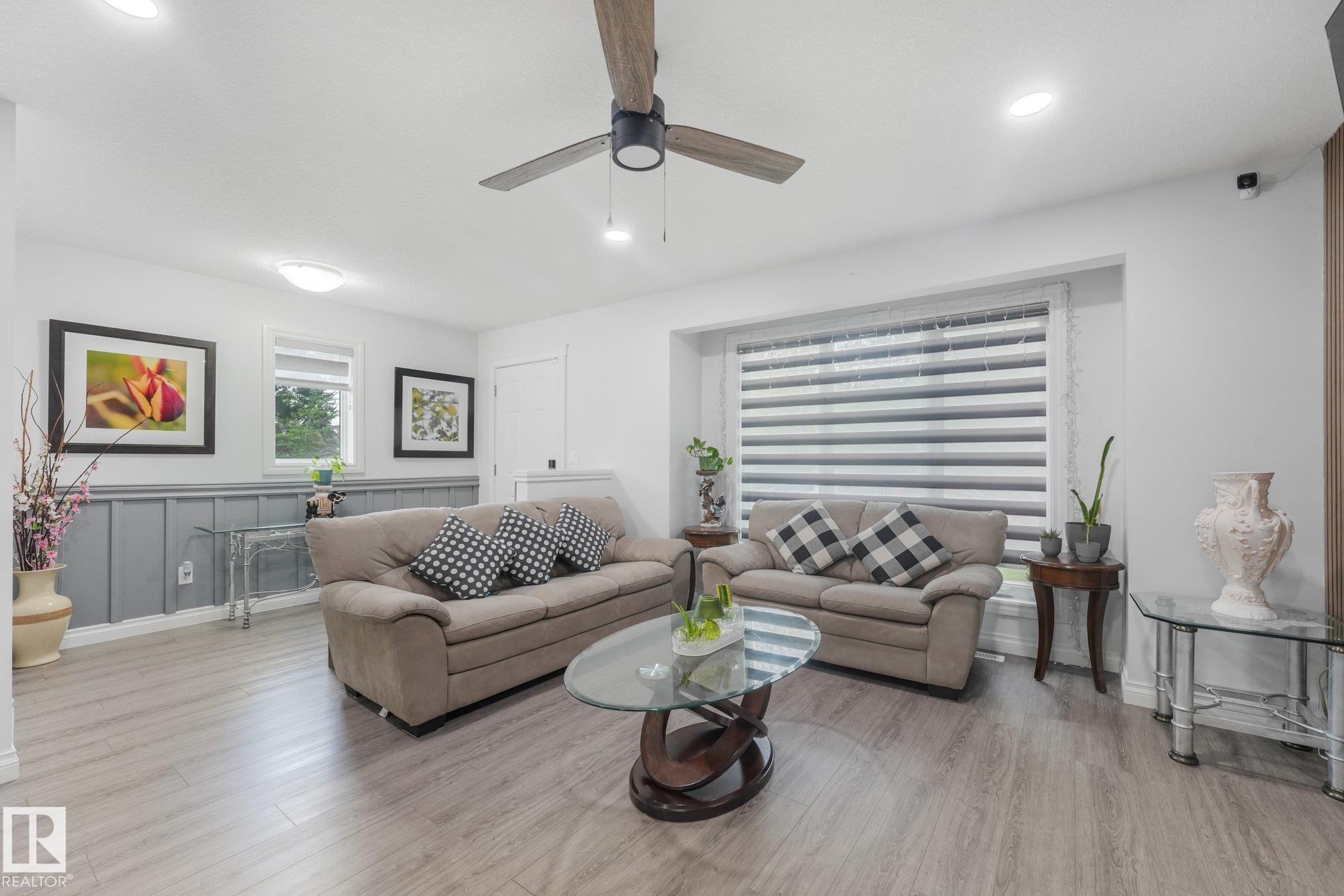 Wood-finish flooring, recessed lighting, ceiling fan, large window with blinds, and wainscoting - 12843 67 Street Nw, Edmonton, AB