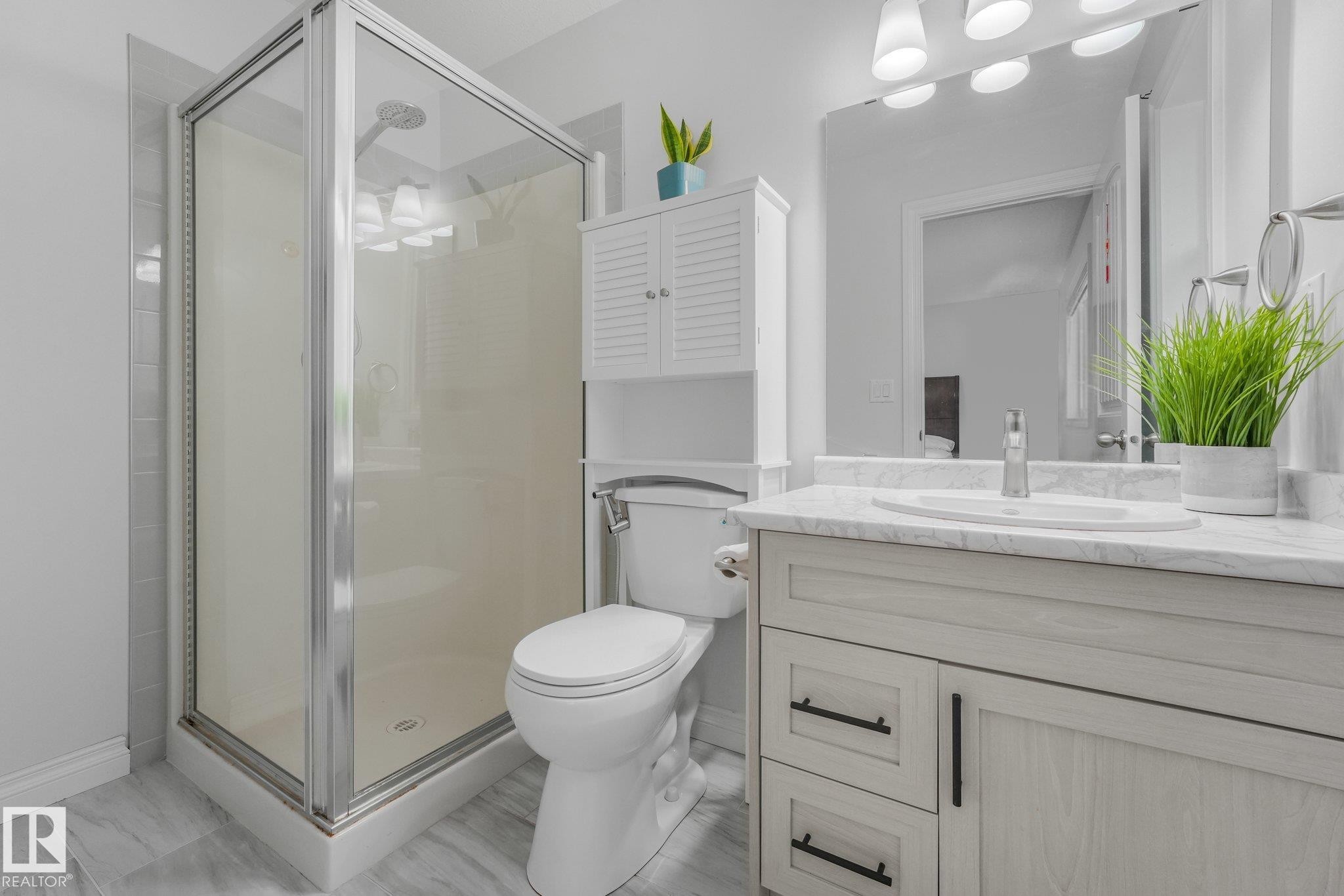 Glass-enclosed shower with a chrome shower head and tiled surround - 12843 67 Street Nw, Edmonton, AB