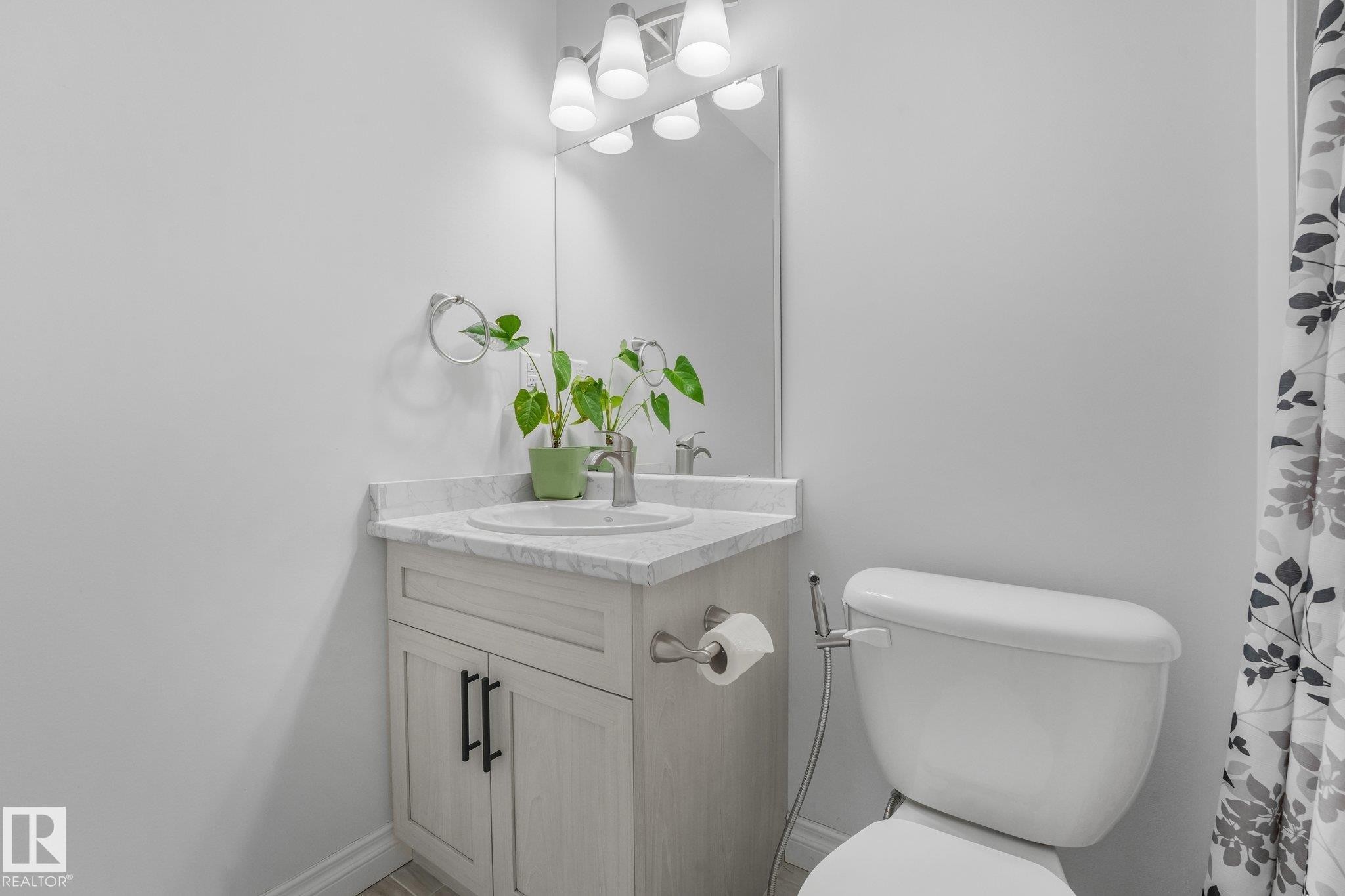 Single vanity with a white countertop and integrated sink, chrome faucet, and a wall-mounted mirror - 12843 67 Street Nw, Edmonton, AB