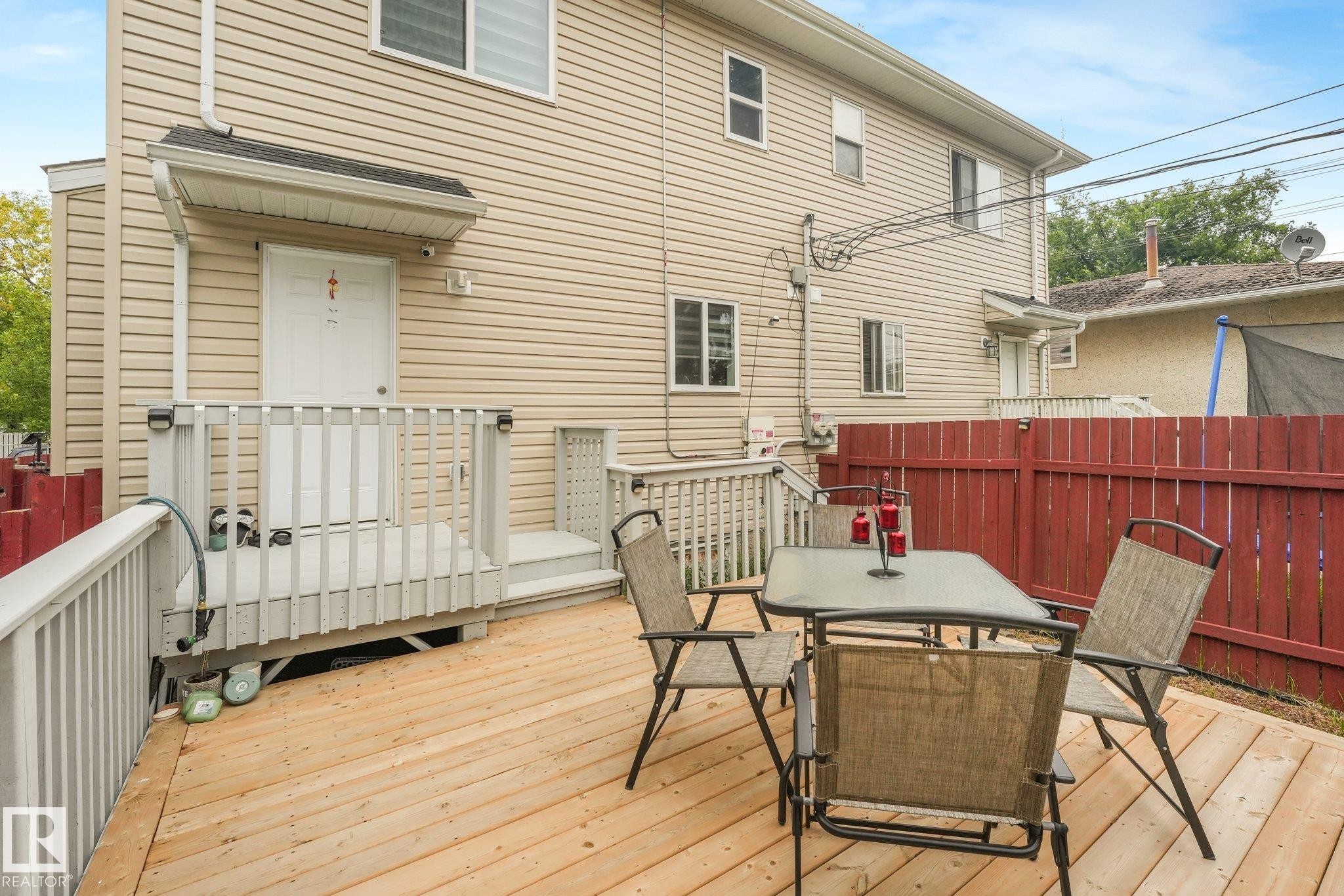 Expansive wood deck with a red privacy fence and exterior siding - 12843 67 Street Nw, Edmonton, AB