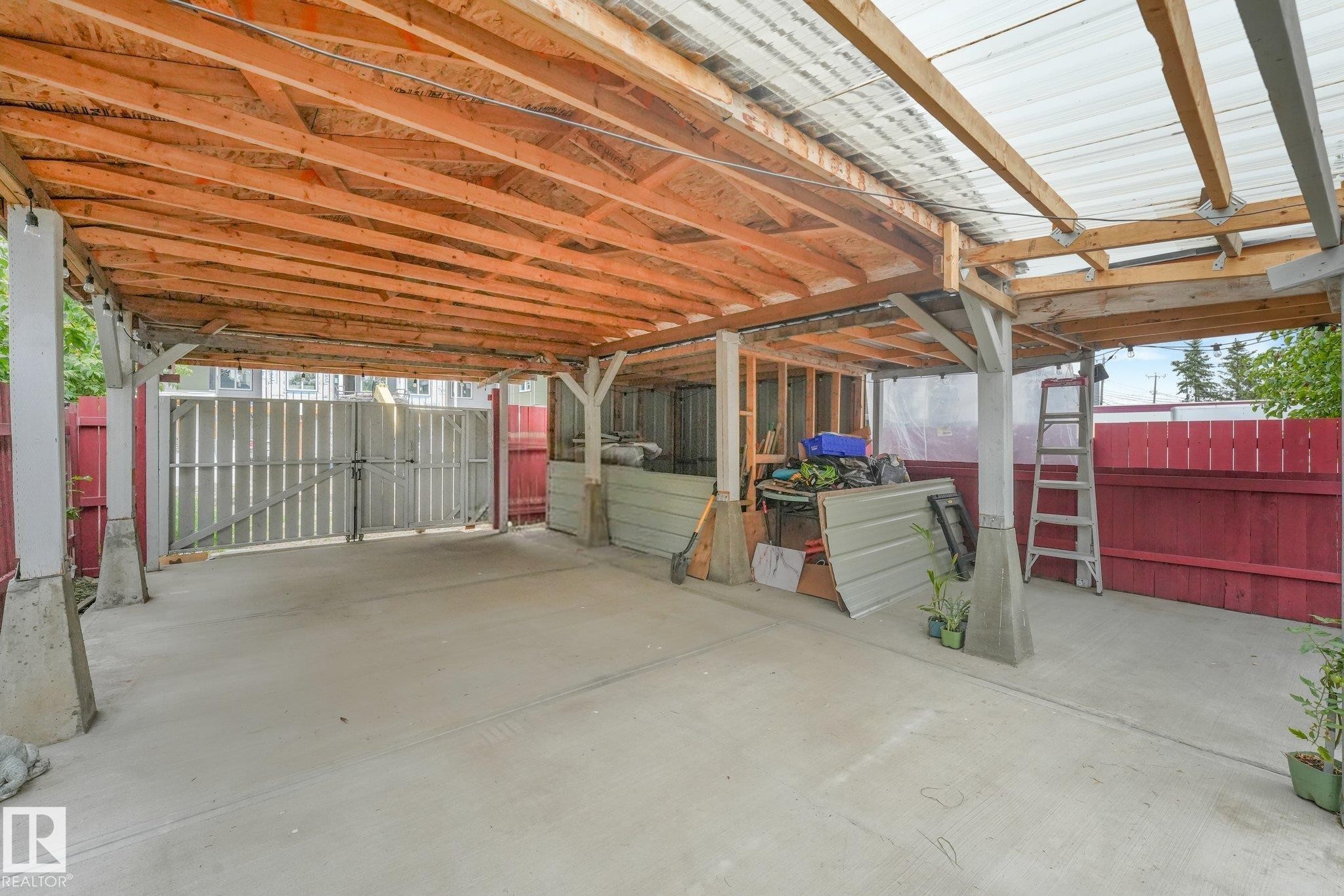Concrete paved area with a wood-framed overhead structure, featuring a corrugated translucent roof - 12843 67 Street Nw, Edmonton, AB