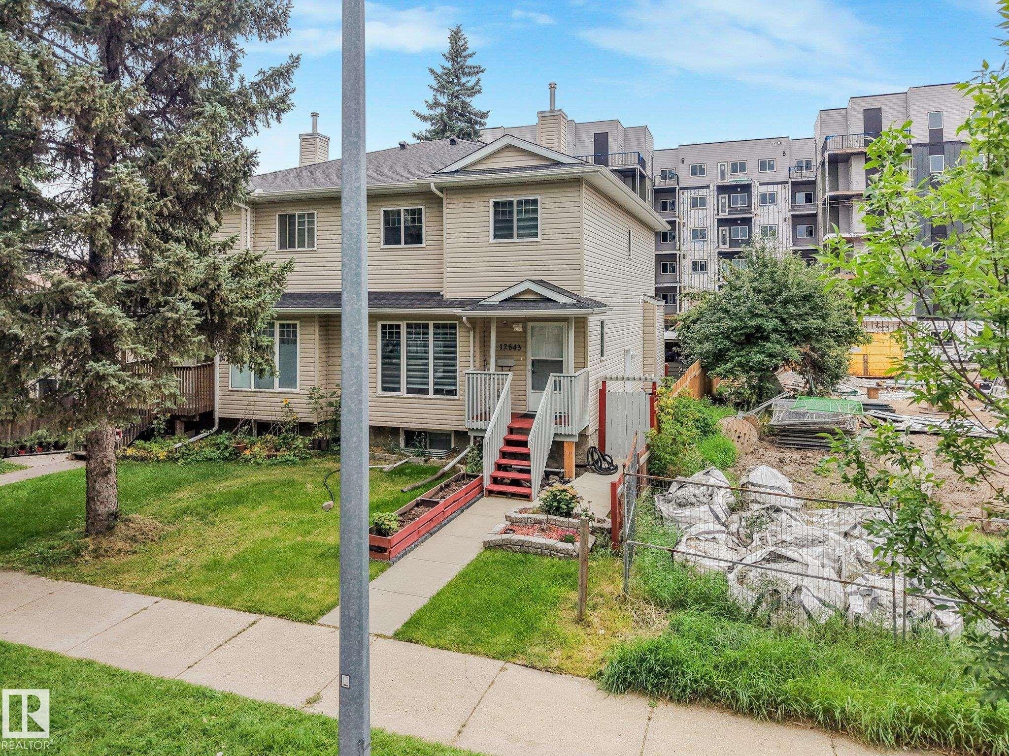 Two-story exterior with light-colored siding, a pitched roof, and a front entry with red-painted stairs - 12843 67 Street Nw, Edmonton, AB