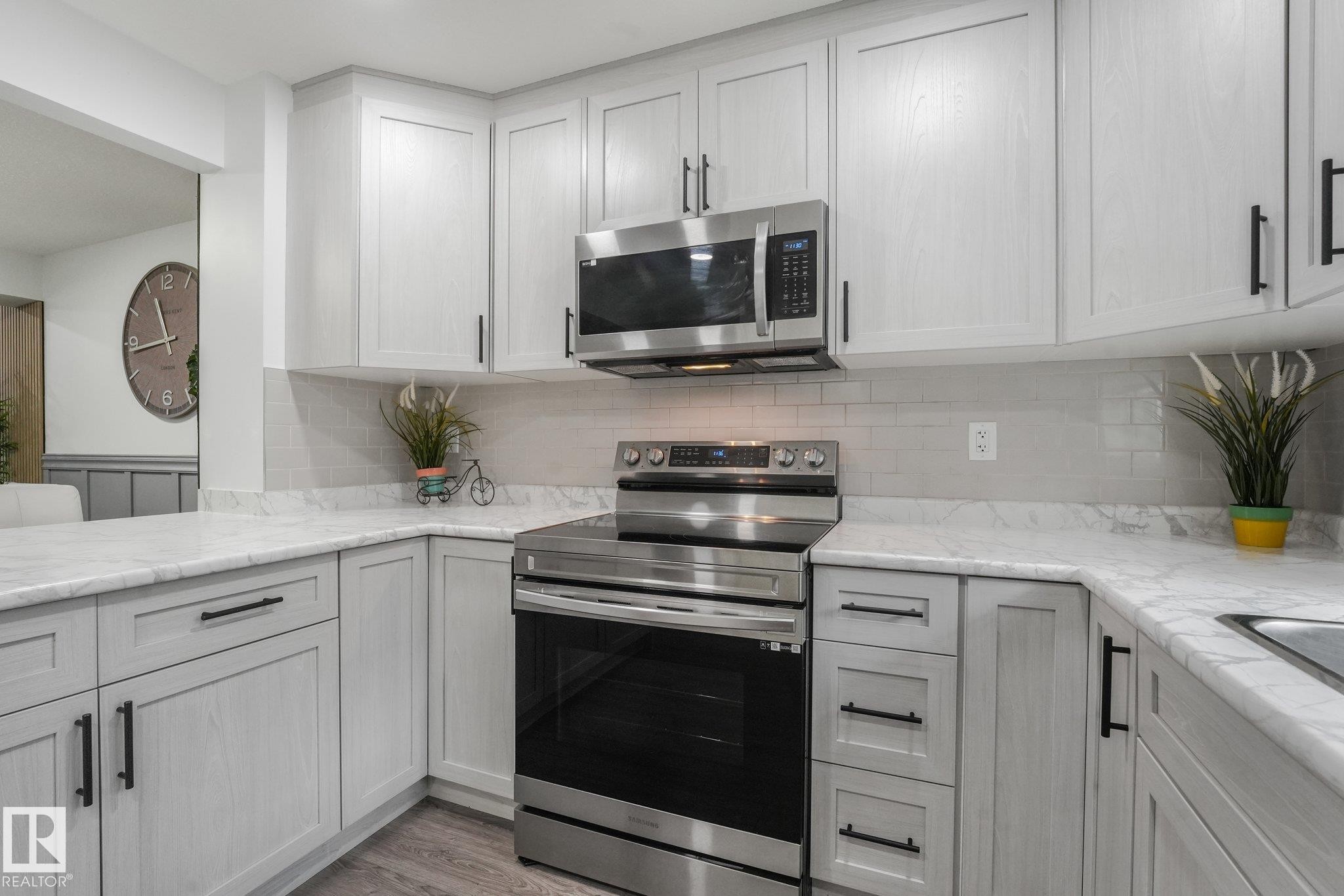 Grey shaker cabinetry with matte black hardware, stainless steel appliances, marble-finish countertops, and subway tile backsplash - 12843 67 Street Nw, Edmonton, AB