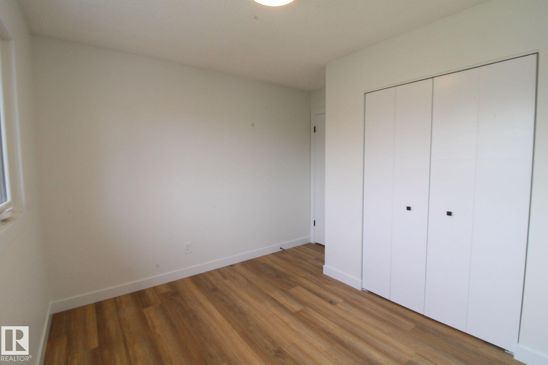 Wood-finish flooring, white walls, and a built-in closet with white bifold doors - 4224 110 Street Nw, Edmonton, AB