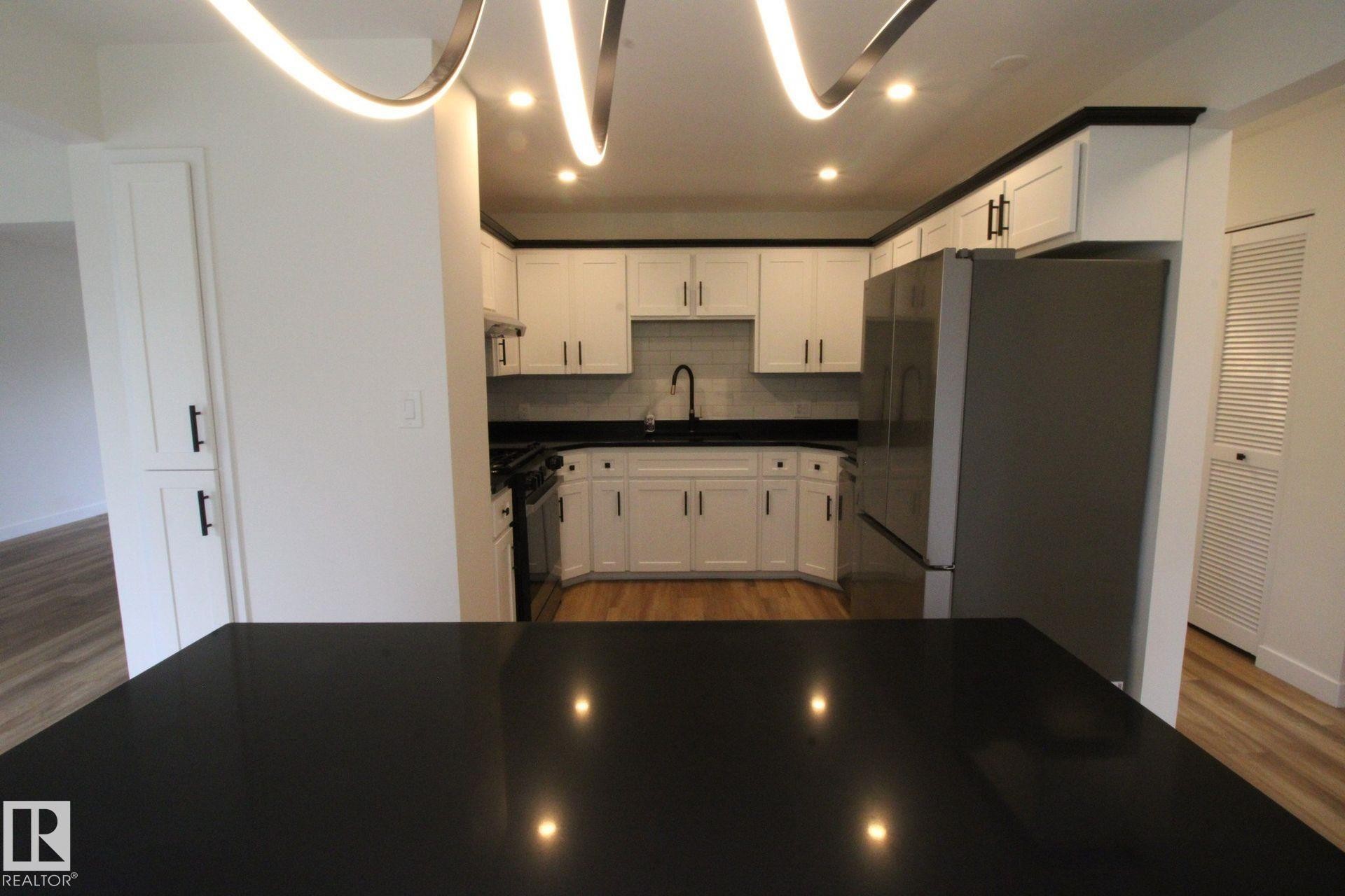 Modern kitchen featuring white cabinetry, dark countertops, recessed lighting, and wood-finish flooring - 4224 110 Street Nw, Edmonton, AB