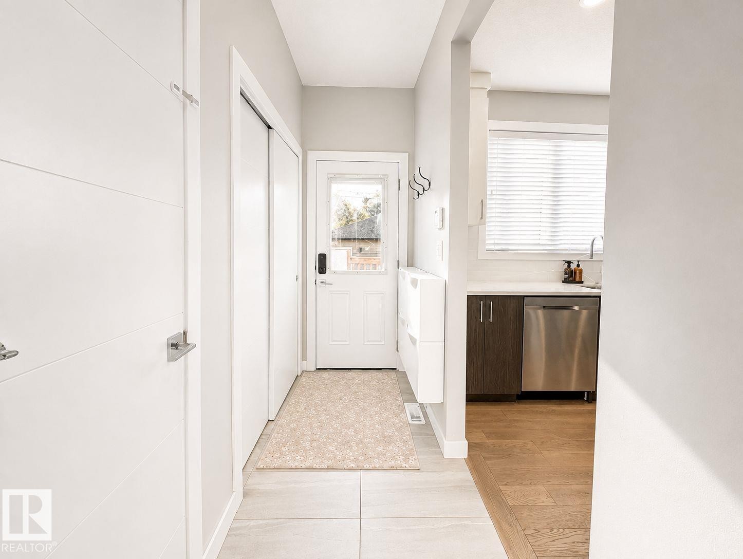 Entryway with light tile flooring, leading to a kitchen with wood-finish flooring - 10516 76 Street Nw, Edmonton, AB