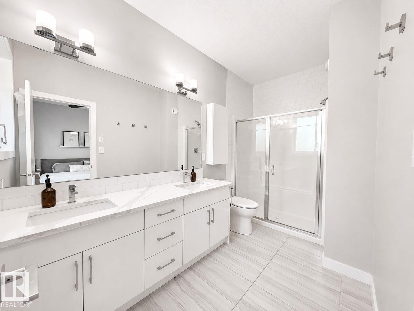 Dual vanity with integrated sinks, quartz-finish countertop, and full-width mirror - 10516 76 Street Nw, Edmonton, AB