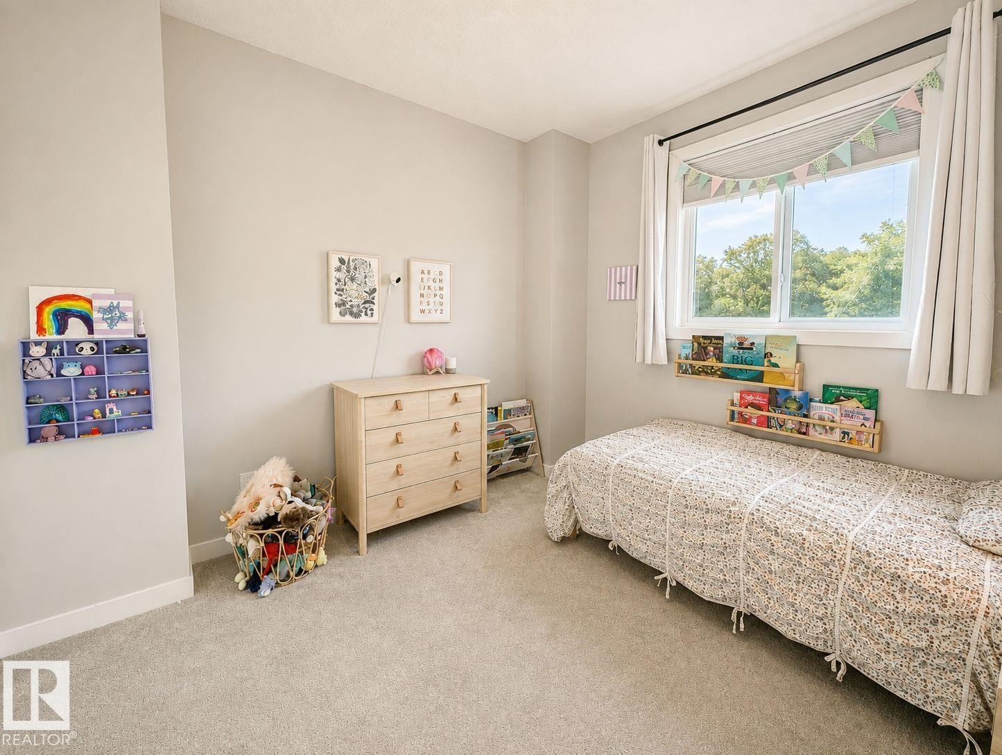 Neutral tone wall paint, light-toned carpet flooring, a large window, a wall-mounted display shelf, and built-in wall shelving - 10516 76 Street Nw, Edmonton, AB