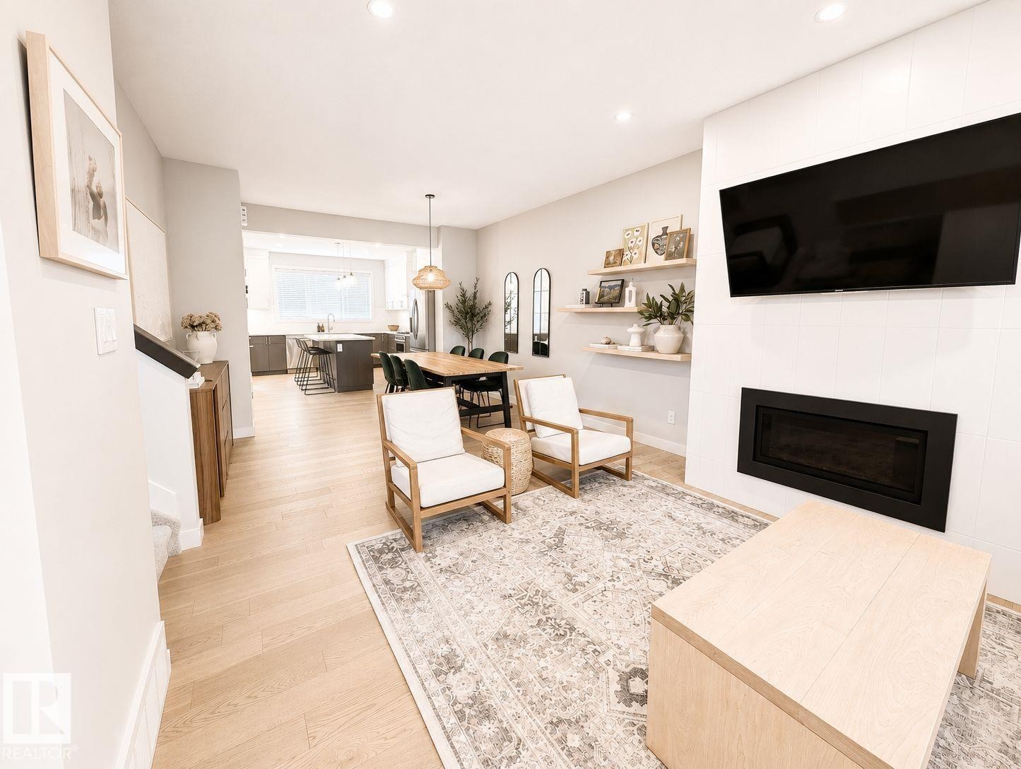 Open-concept living space featuring wood-finish flooring, recessed lighting, and a linear electric fireplace - 10516 76 Street Nw, Edmonton, AB