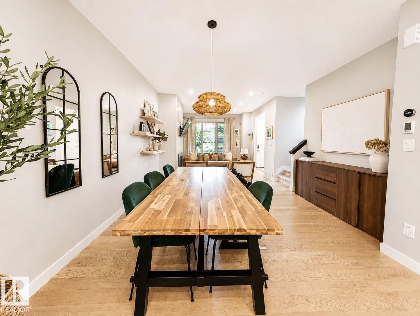 Open-concept dining area featuring wood-finish flooring, a contemporary pendant light fixture, and a built-in wood-tone credenza - 10516 76 Street Nw, Edmonton, AB