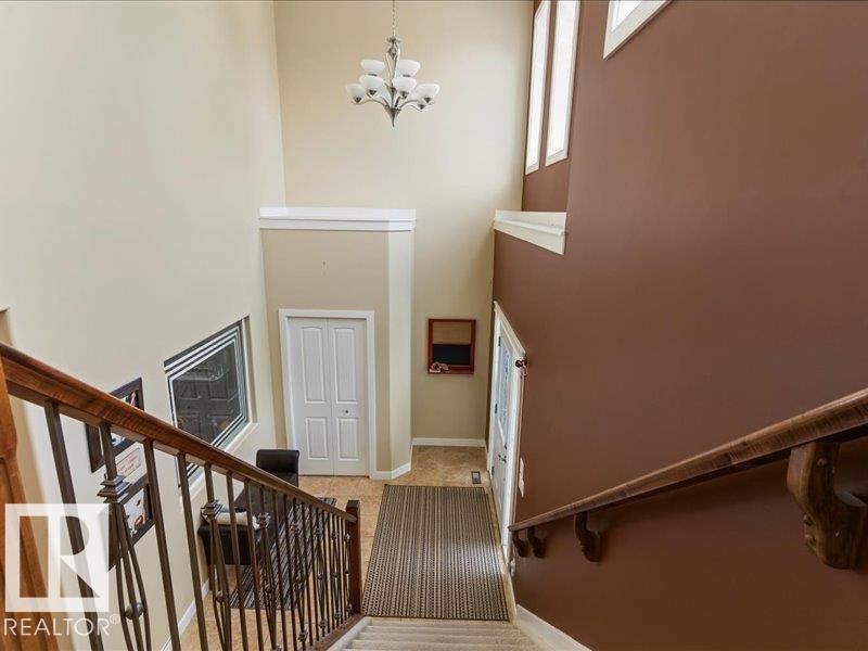 Two-story foyer with a chandelier and multiple windows - 496 Ravine Court, Devon, AB
