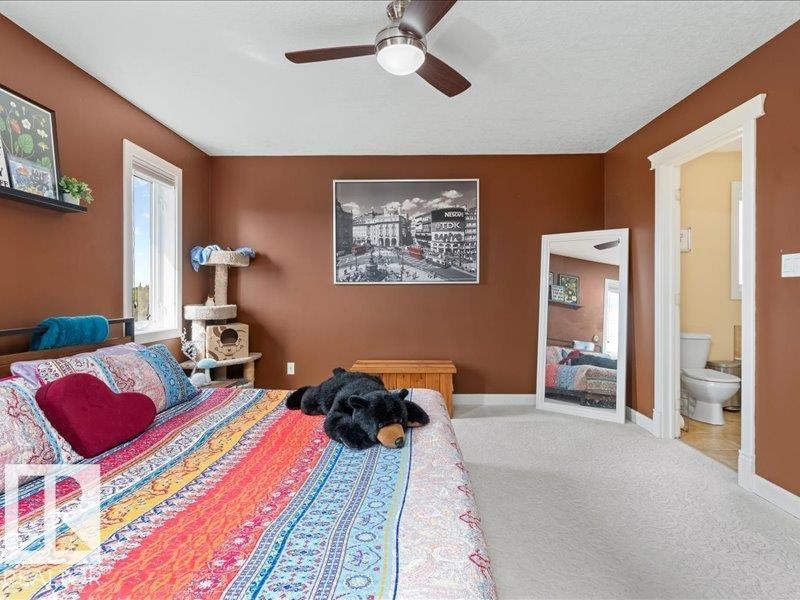 Hardwood headboard with a floating shelf, ceiling fan, and carpeted flooring - 496 Ravine Court, Devon, AB