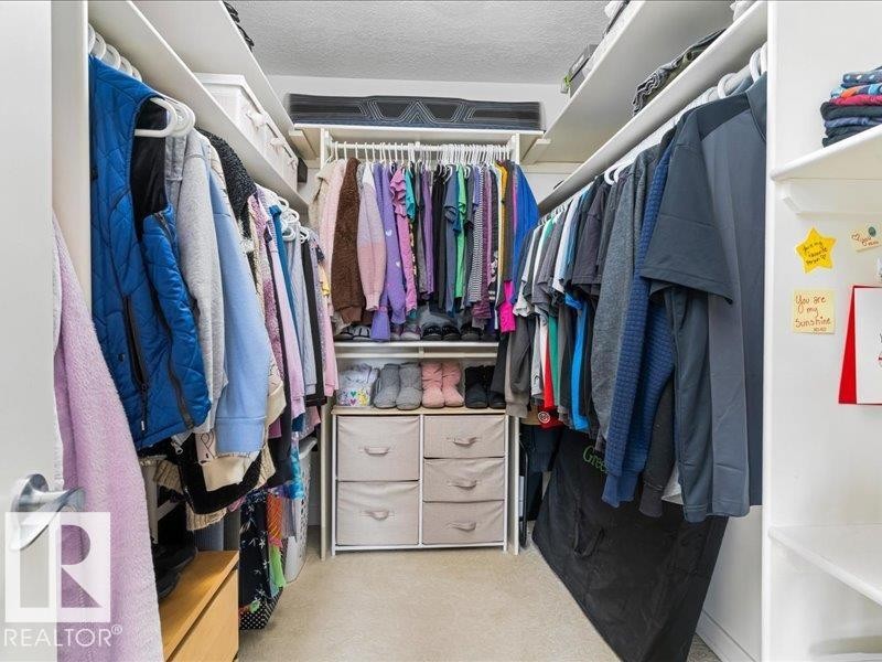 Built-in closet system featuring multiple hanging rods and integrated shelving - 496 Ravine Court, Devon, AB