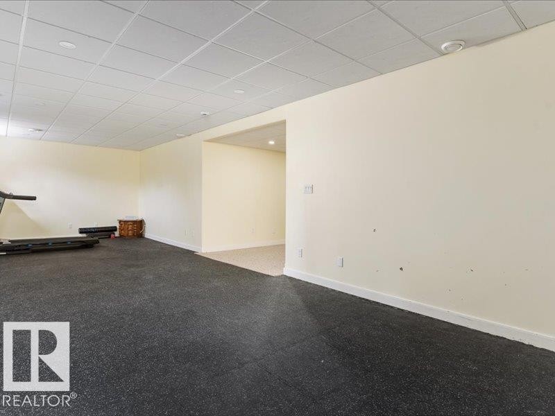 Expansive room featuring commercial-grade flooring, dropped ceiling with recessed lighting, and neutral wall tones - 496 Ravine Court, Devon, AB