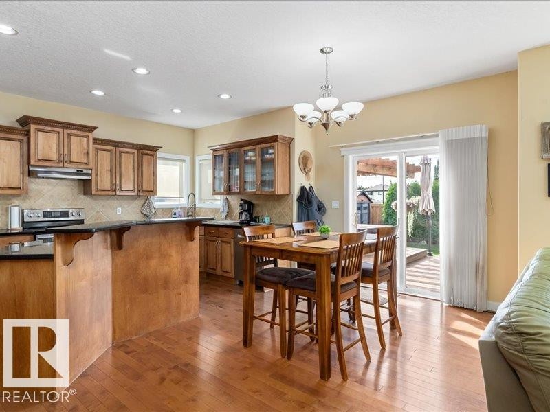 Kitchen featuring wood-finish cabinetry, dark countertops, built-in stainless steel appliances, and recessed lighting - 496 Ravine Court, Devon, AB