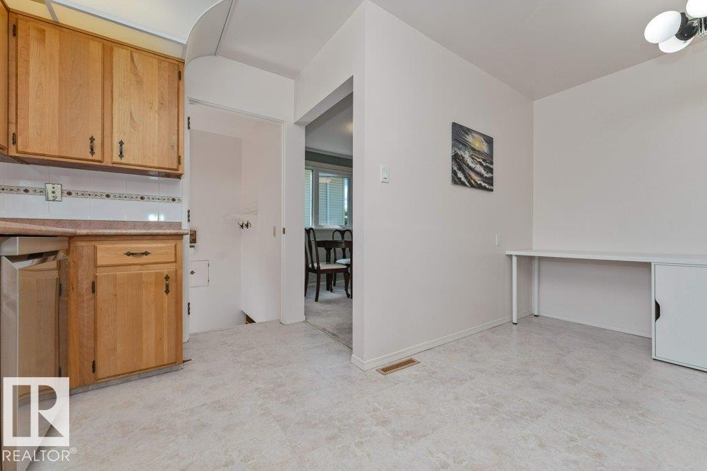 Kitchen area with light wood-finish cabinetry, a built-in dishwasher, and a light-toned countertop - 11415 56 Avenue Nw, Edmonton, AB