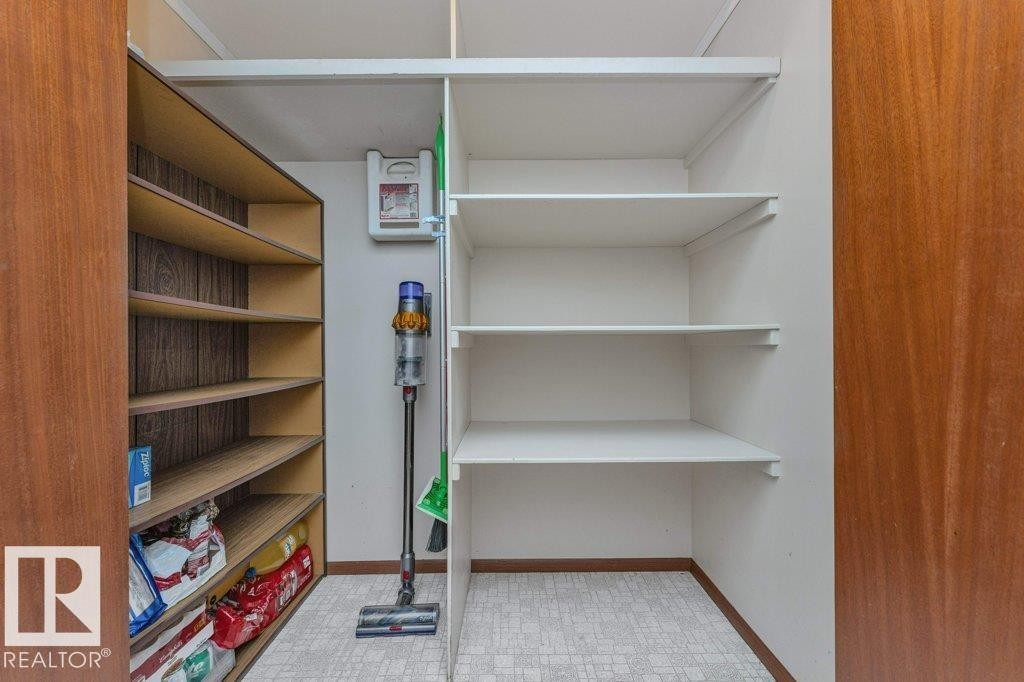 Huge pantry with motion sensor light. Built-in shelving with adjustable white shelves and wood-finish shelving. - 11415 56 Avenue Nw, Edmonton, AB