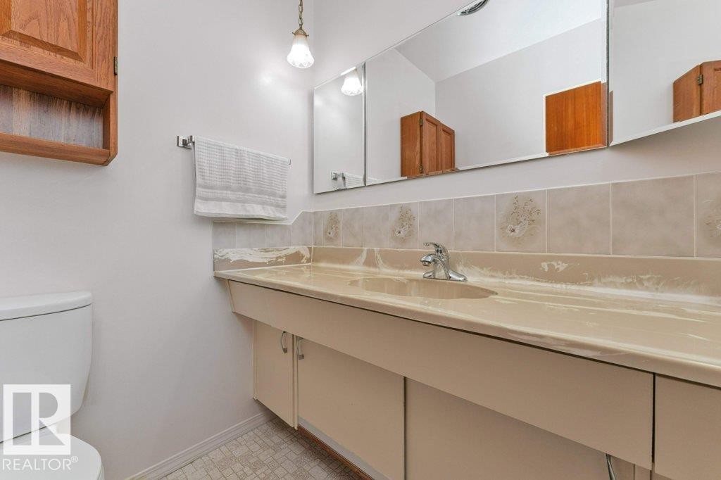 Bathroom vanity with integrated sink, chrome faucet, and mirrored medicine cabinet - 11415 56 Avenue Nw, Edmonton, AB