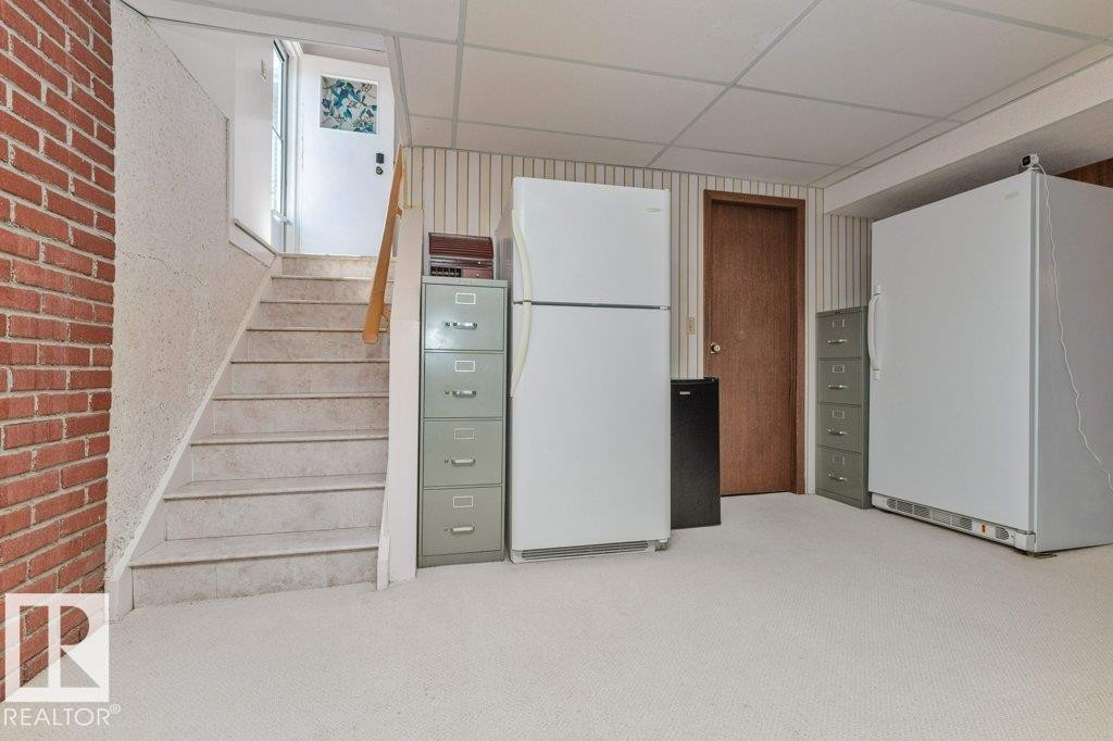 Carpeted flooring extending to the staircase featuring a wood handrail - 11415 56 Avenue Nw, Edmonton, AB