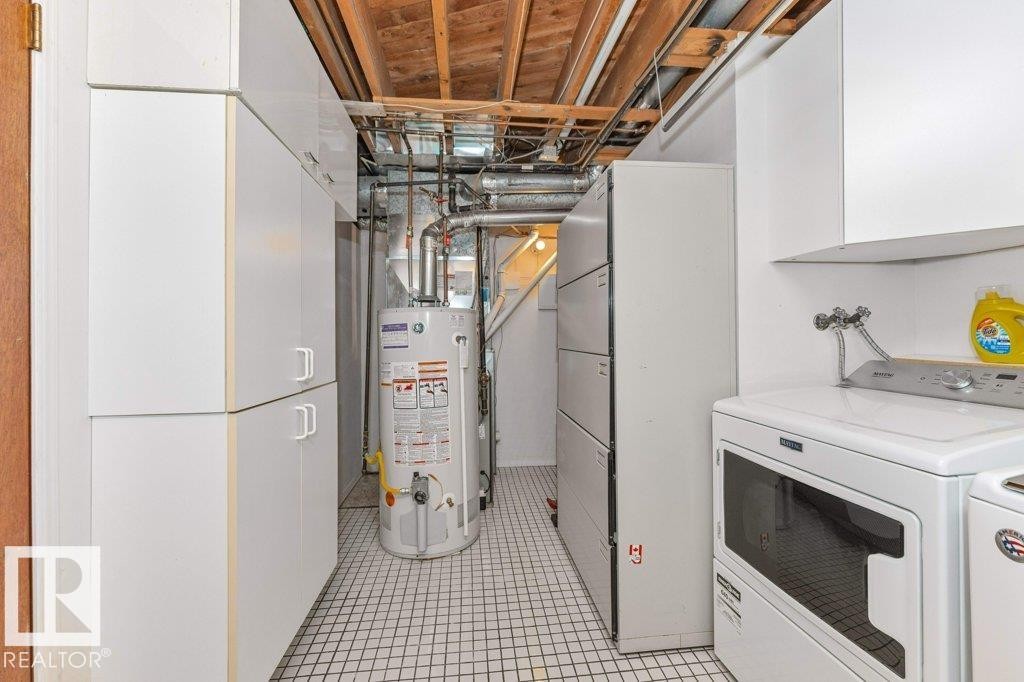 Utility room featuring extensive white cabinetry, a tiled floor, and exposed ceiling joists - 11415 56 Avenue Nw, Edmonton, AB