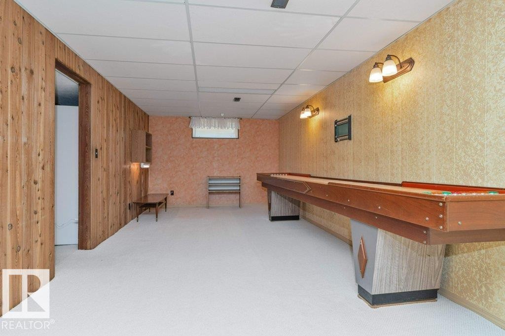 Lower-level recreation space featuring wood paneling, textured wall finishes, and recessed lighting - 11415 56 Avenue Nw, Edmonton, AB
