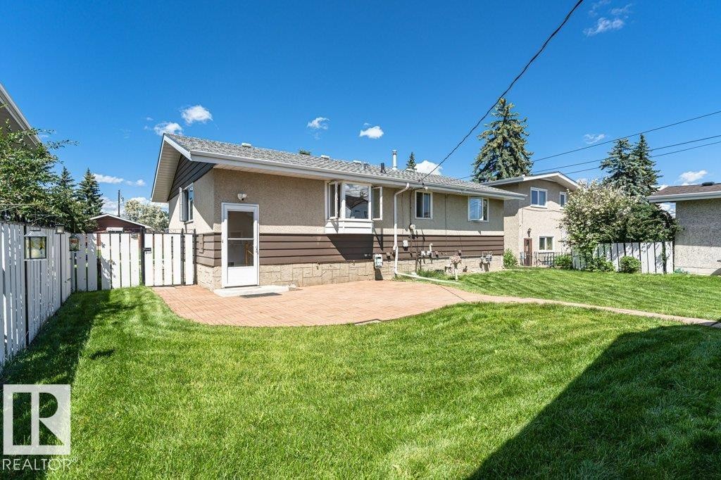 Expansive rear yard featuring a curved paver patio and verdant lawn - 11415 56 Avenue Nw, Edmonton, AB