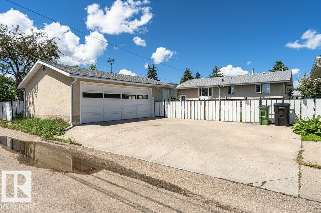 Detached garage featuring a white panel door with windows, stucco exterior, and a shingled roof - 11415 56 Avenue Nw, Edmonton, AB