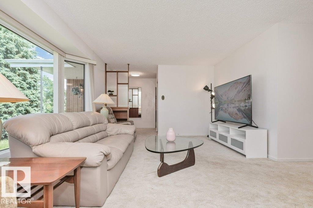 Living area featuring light-toned carpet flooring and white painted walls - 11415 56 Avenue Nw, Edmonton, AB