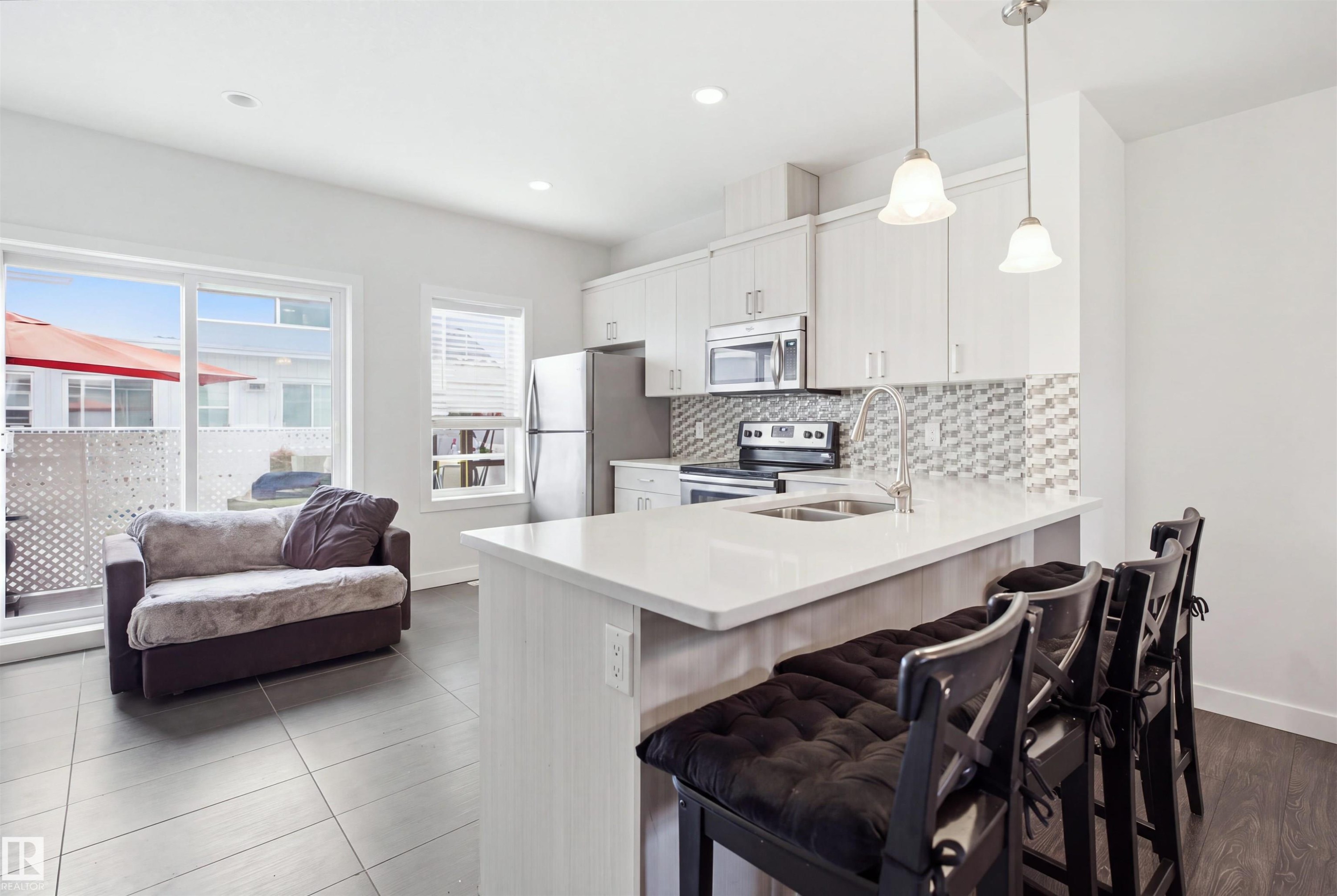 Kitchen with white cabinetry, stainless steel appliances, and a tiled backsplash - #22 723 172 Street Sw, Edmonton, AB