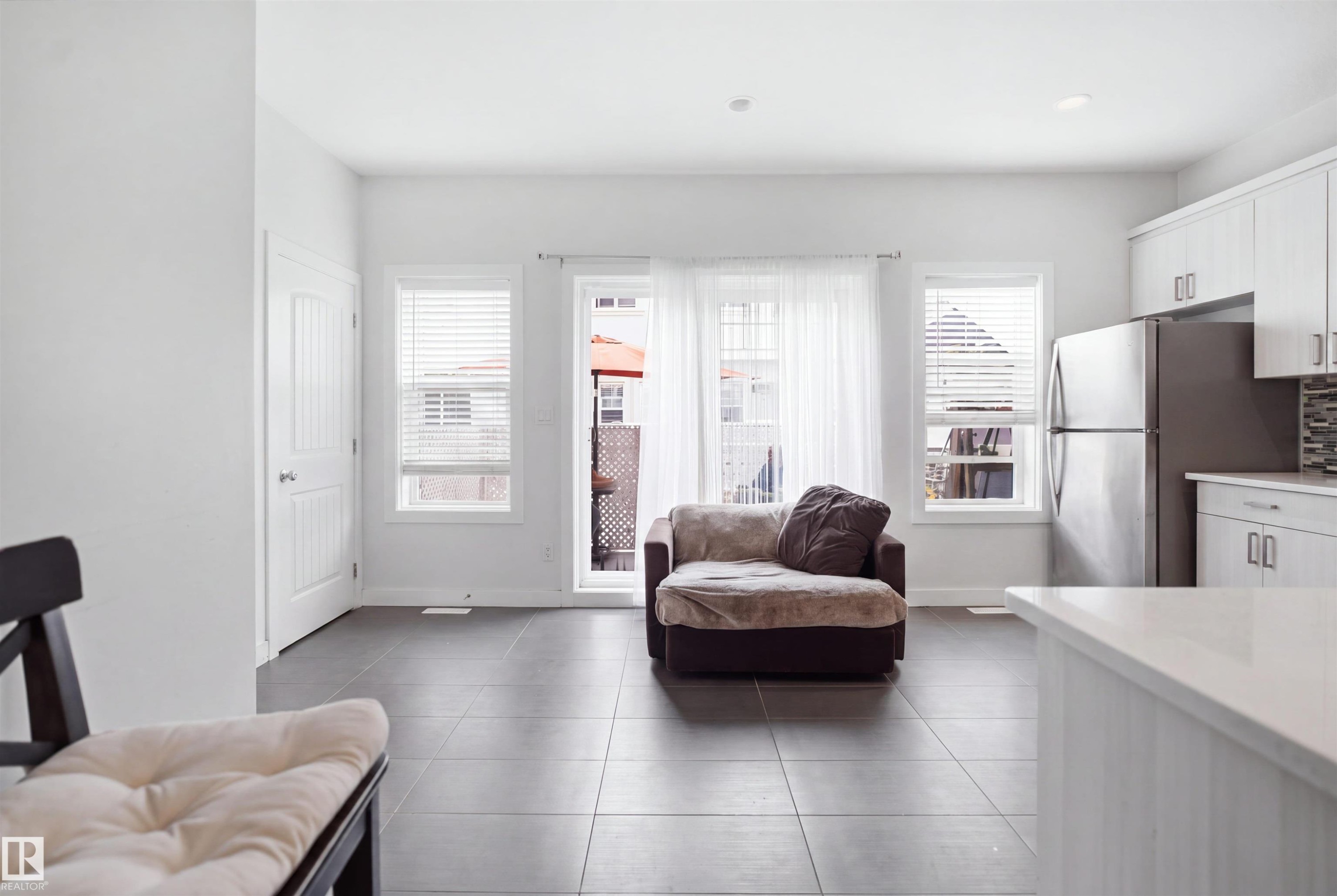 Spacious open-concept room with tile flooring, white walls, and multiple windows - #22 723 172 Street Sw, Edmonton, AB