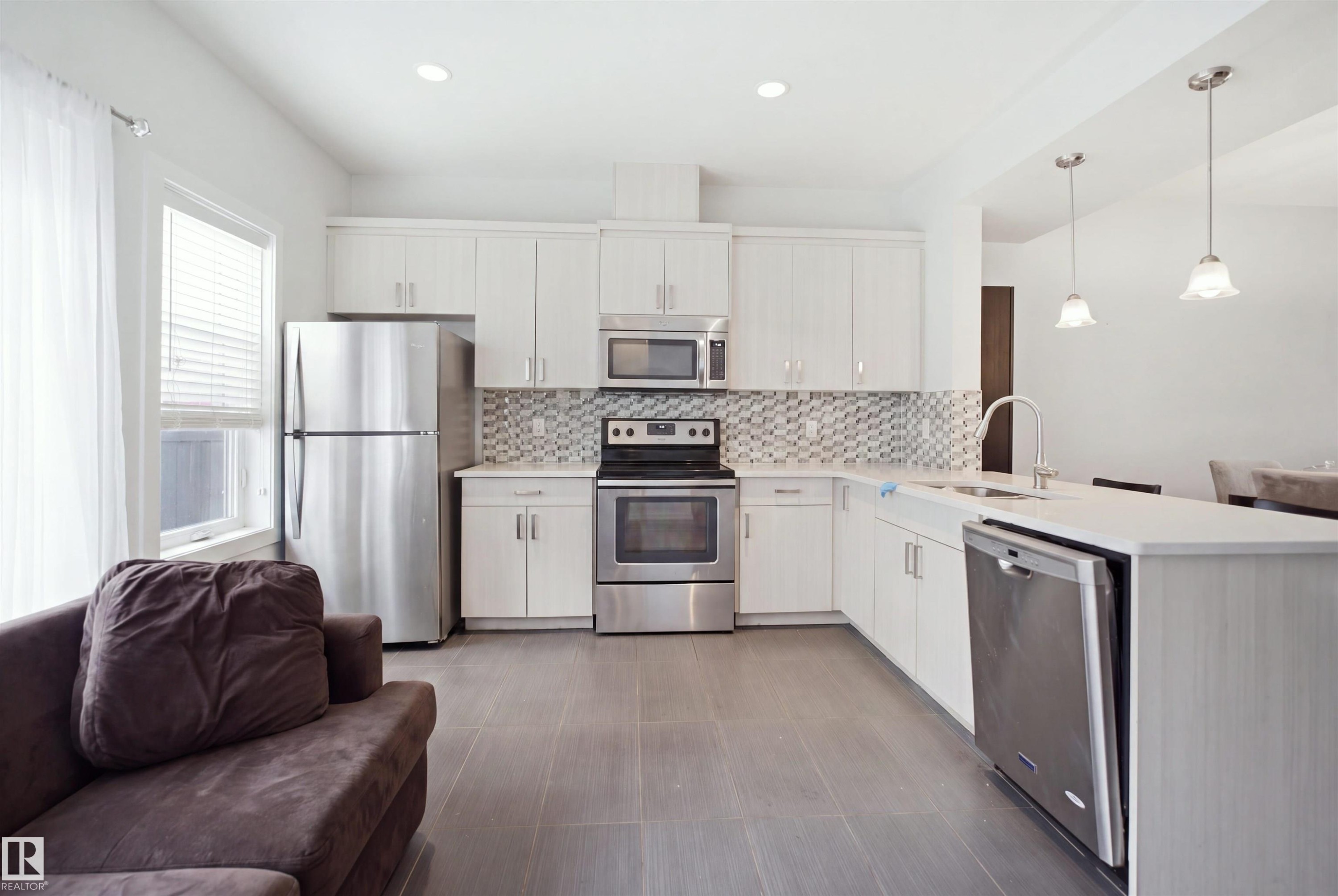 Stainless steel appliances, white cabinetry, mosaic tile backsplash, recessed lighting, and pendant lighting - #22 723 172 Street Sw, Edmonton, AB