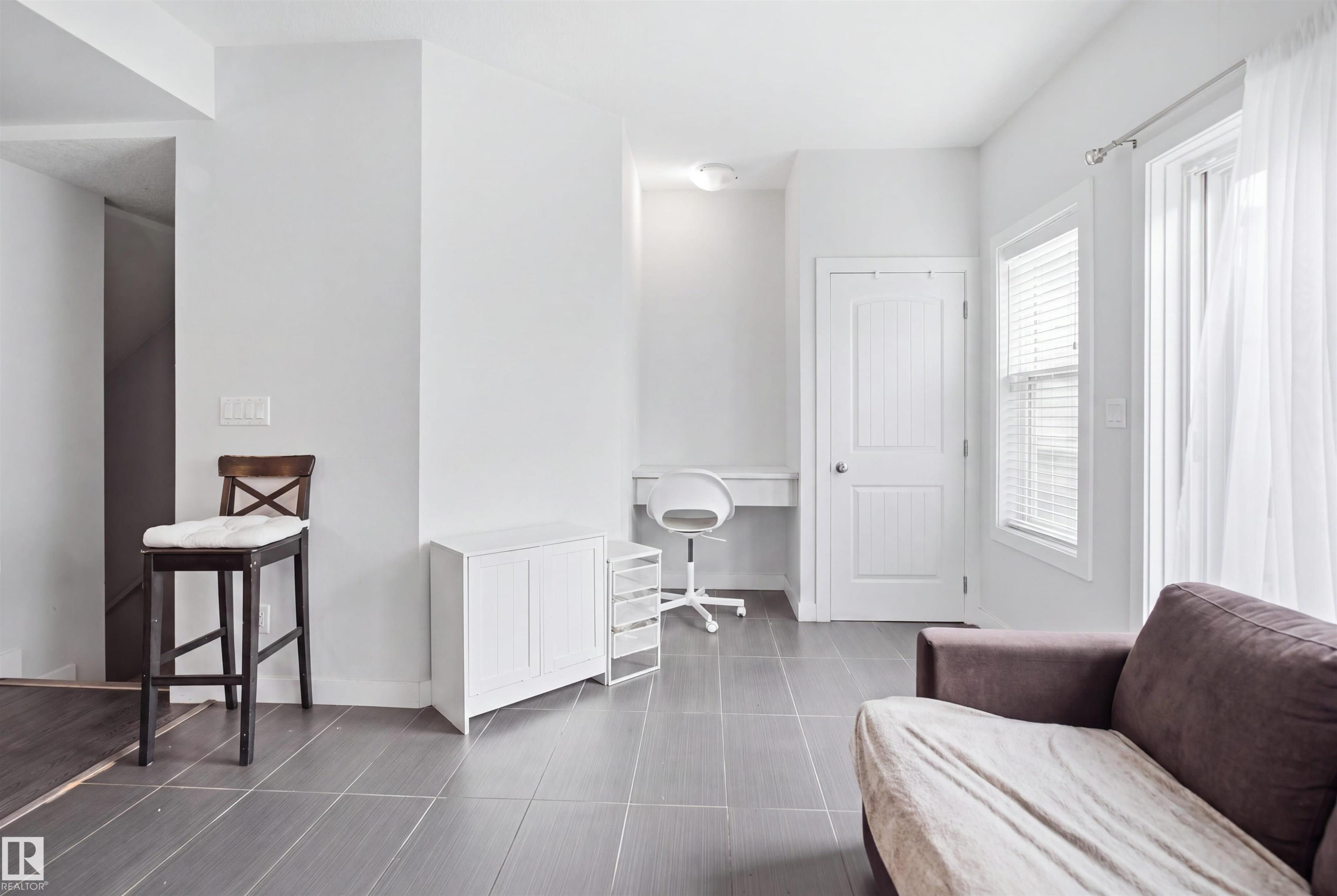 Recessed built-in desk, white paneled door, window with blinds, and tile flooring - #22 723 172 Street Sw, Edmonton, AB
