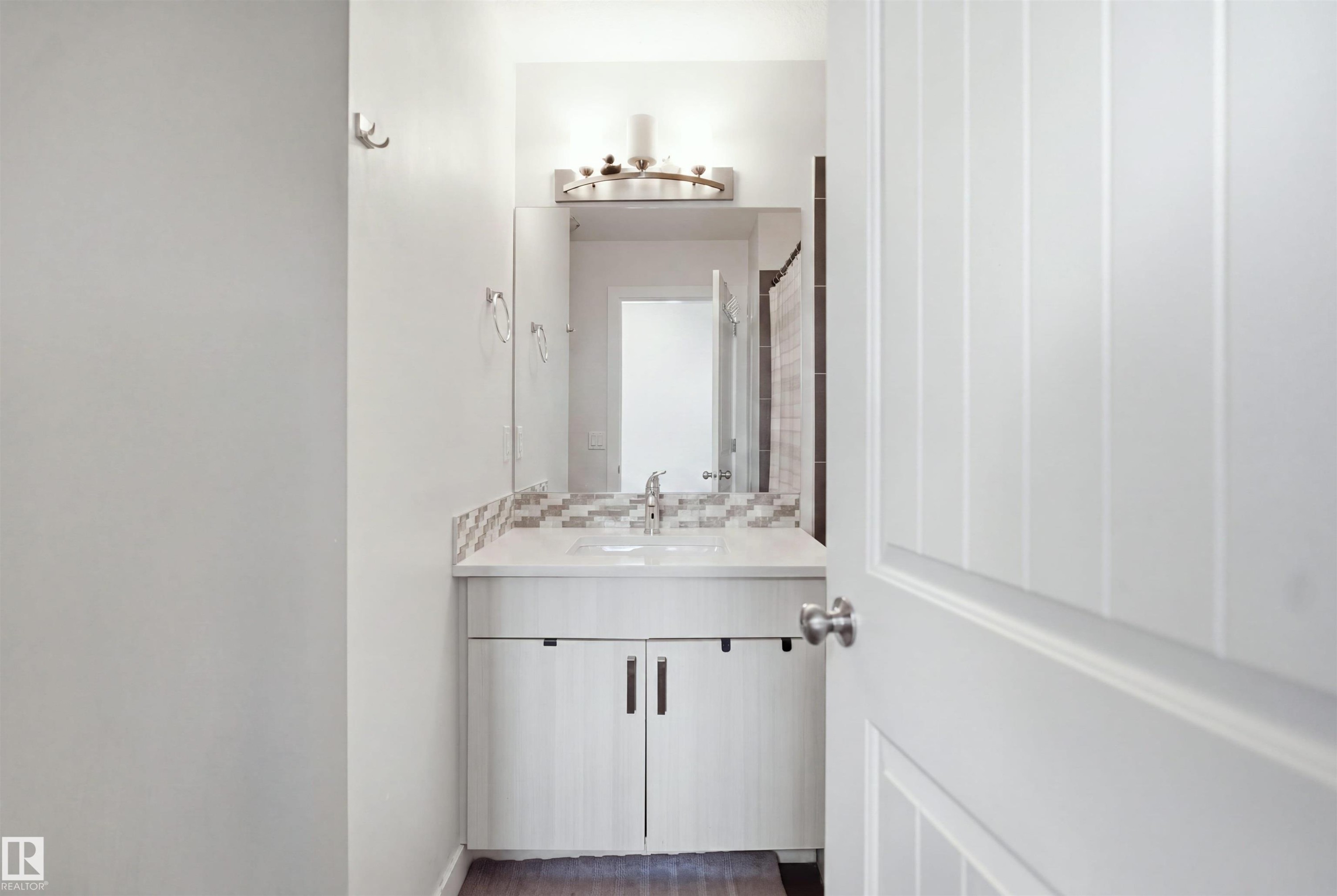 Vanity with a single basin, tiled backsplash, and wall-mounted light fixture - #22 723 172 Street Sw, Edmonton, AB