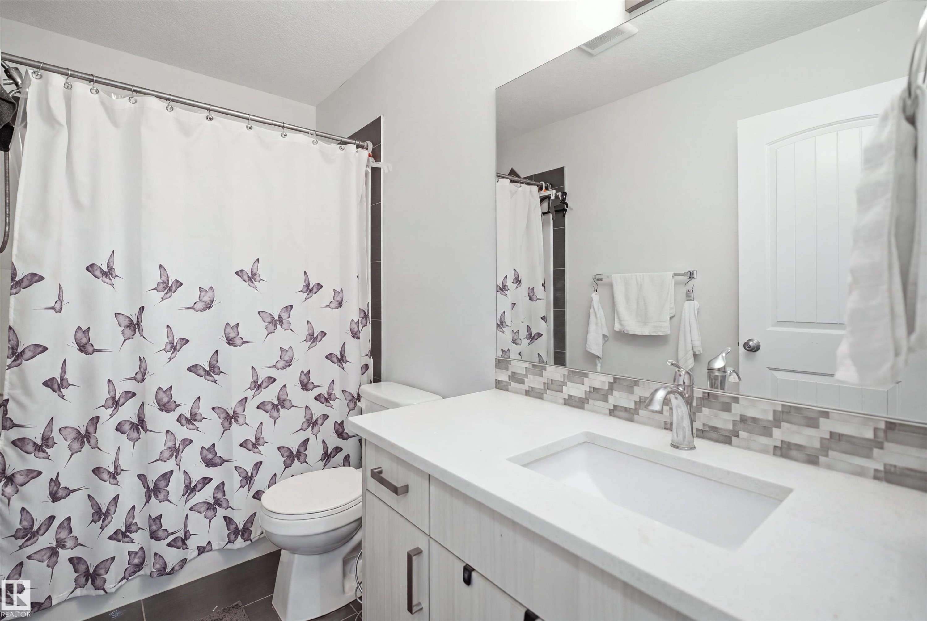 Vanity with an integrated sink, polished chrome faucet, and mosaic tile backsplash - #22 723 172 Street Sw, Edmonton, AB