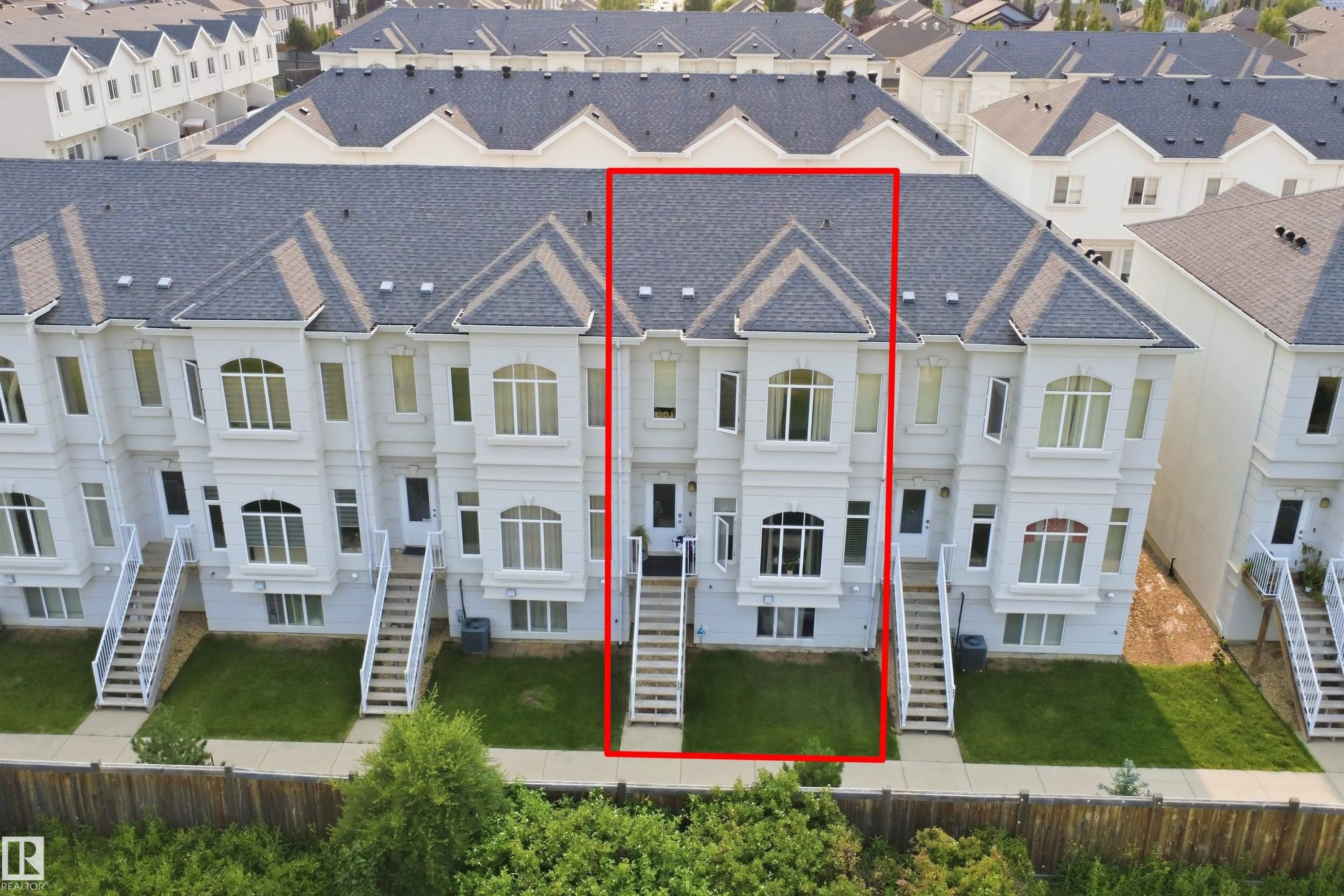 Multi-level townhouse with a dark shingle roof, light-colored exterior siding, and a front entry staircase - #22 723 172 Street Sw, Edmonton, AB