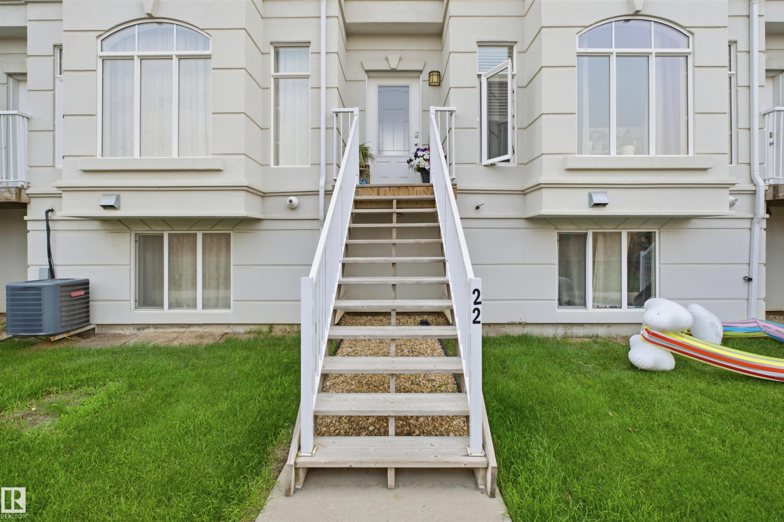 Front exterior featuring a pedestrian entrance with staircase, light-toned siding, and multiple window styles - #22 723 172 Street Sw, Edmonton, AB