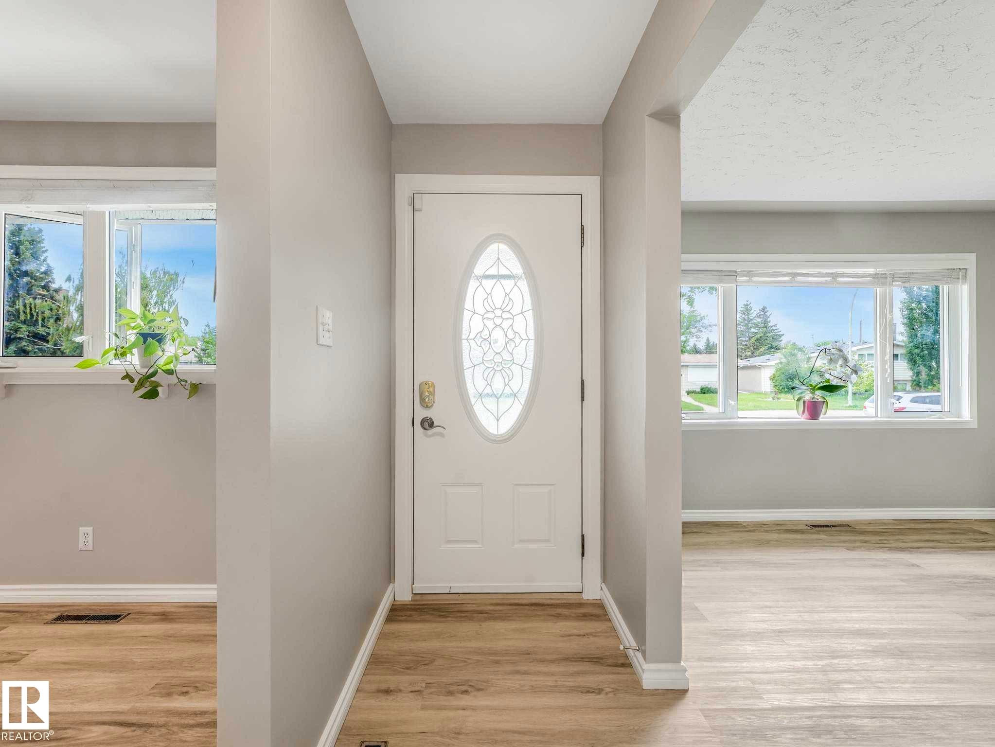 Entryway featuring a white door with an oval leaded glass insert, light wood-finish flooring, and light gray walls - 15916 88B Avenue Nw, Edmonton, AB