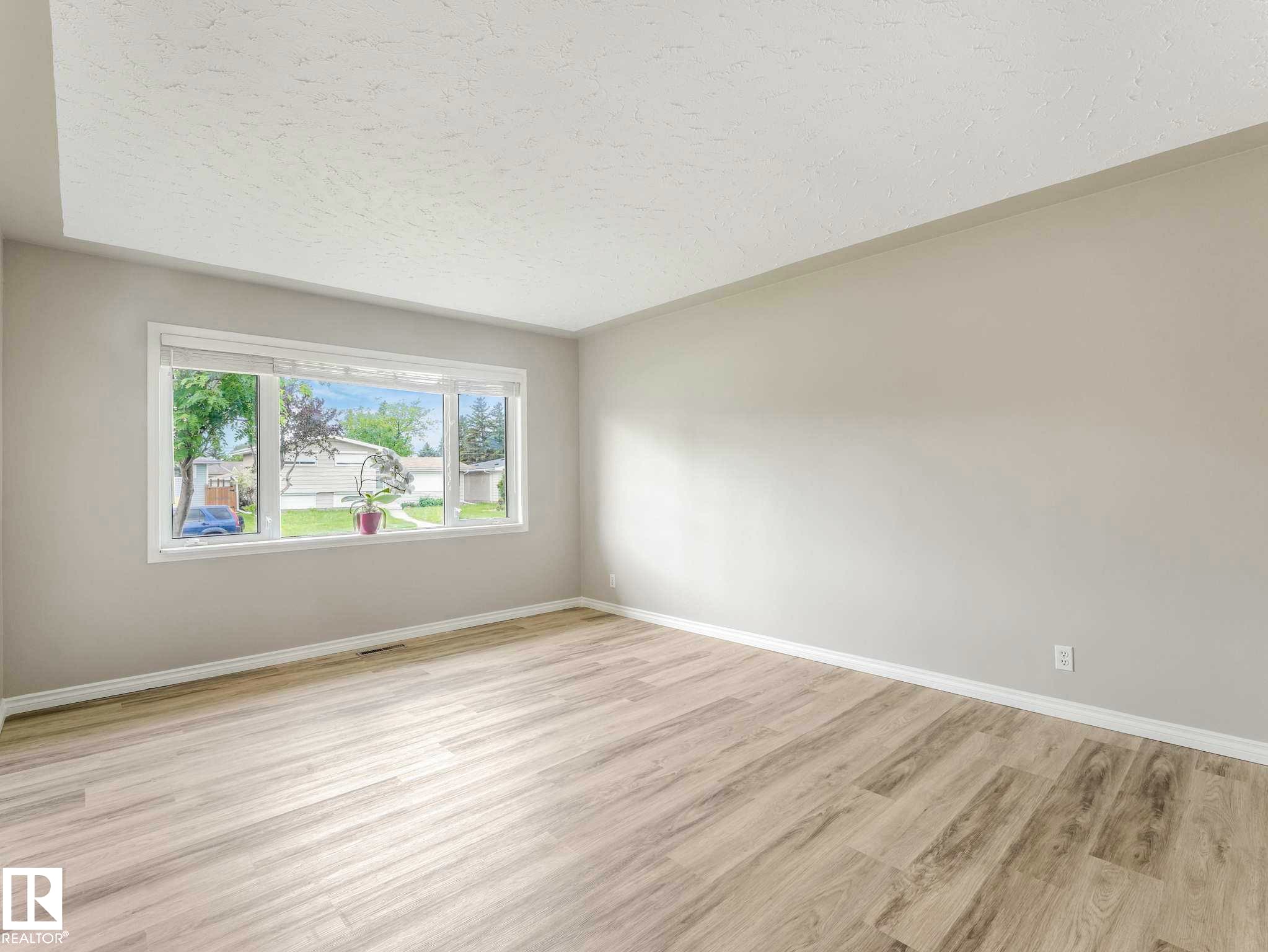 Neutral wall finishes, wood-finish flooring, and a large window with white trim - 15916 88B Avenue Nw, Edmonton, AB