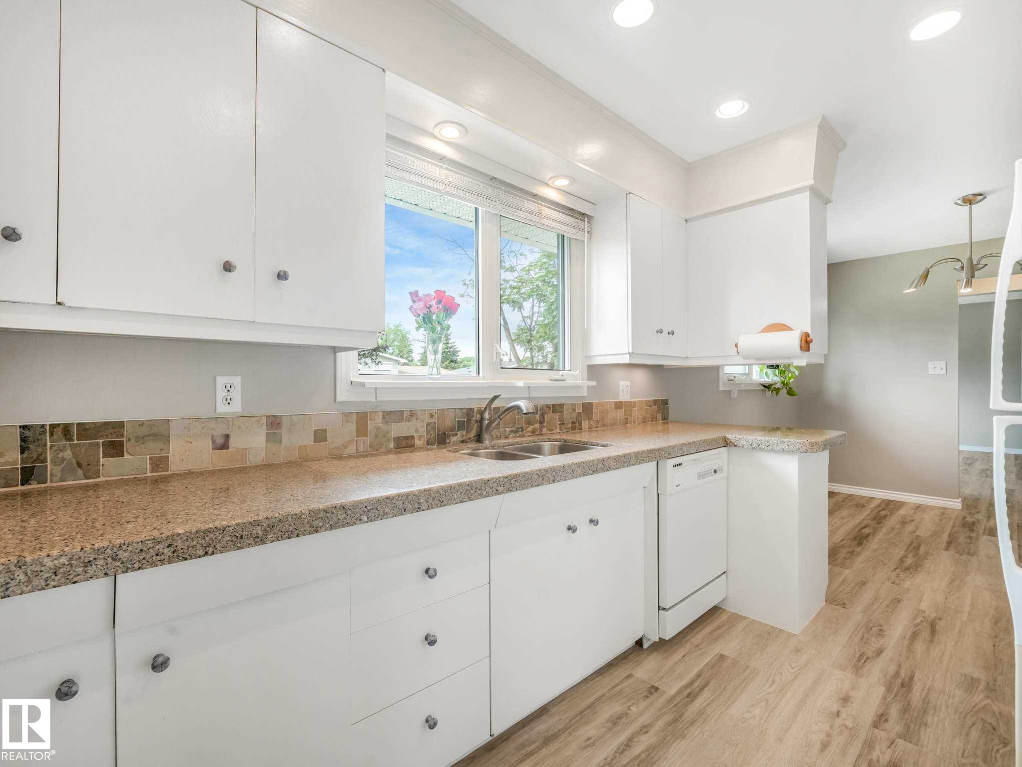 Kitchen featuring white cabinetry, stone-look countertops, a tiled backsplash, and wood-finish flooring - 15916 88B Avenue Nw, Edmonton, AB