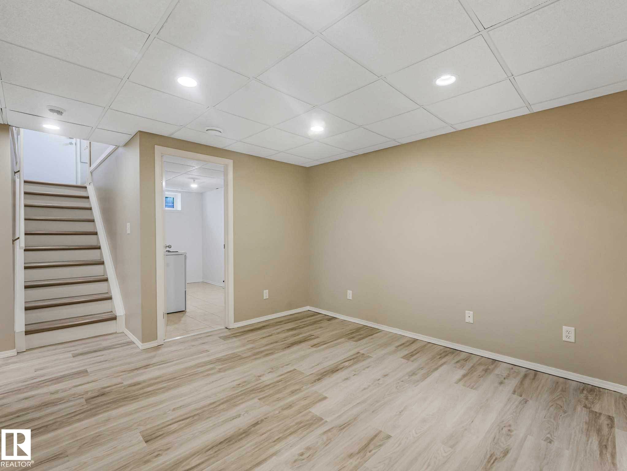 Spacious room featuring wood-finish flooring, recessed lighting, neutral paint, and a drop ceiling - 15916 88B Avenue Nw, Edmonton, AB