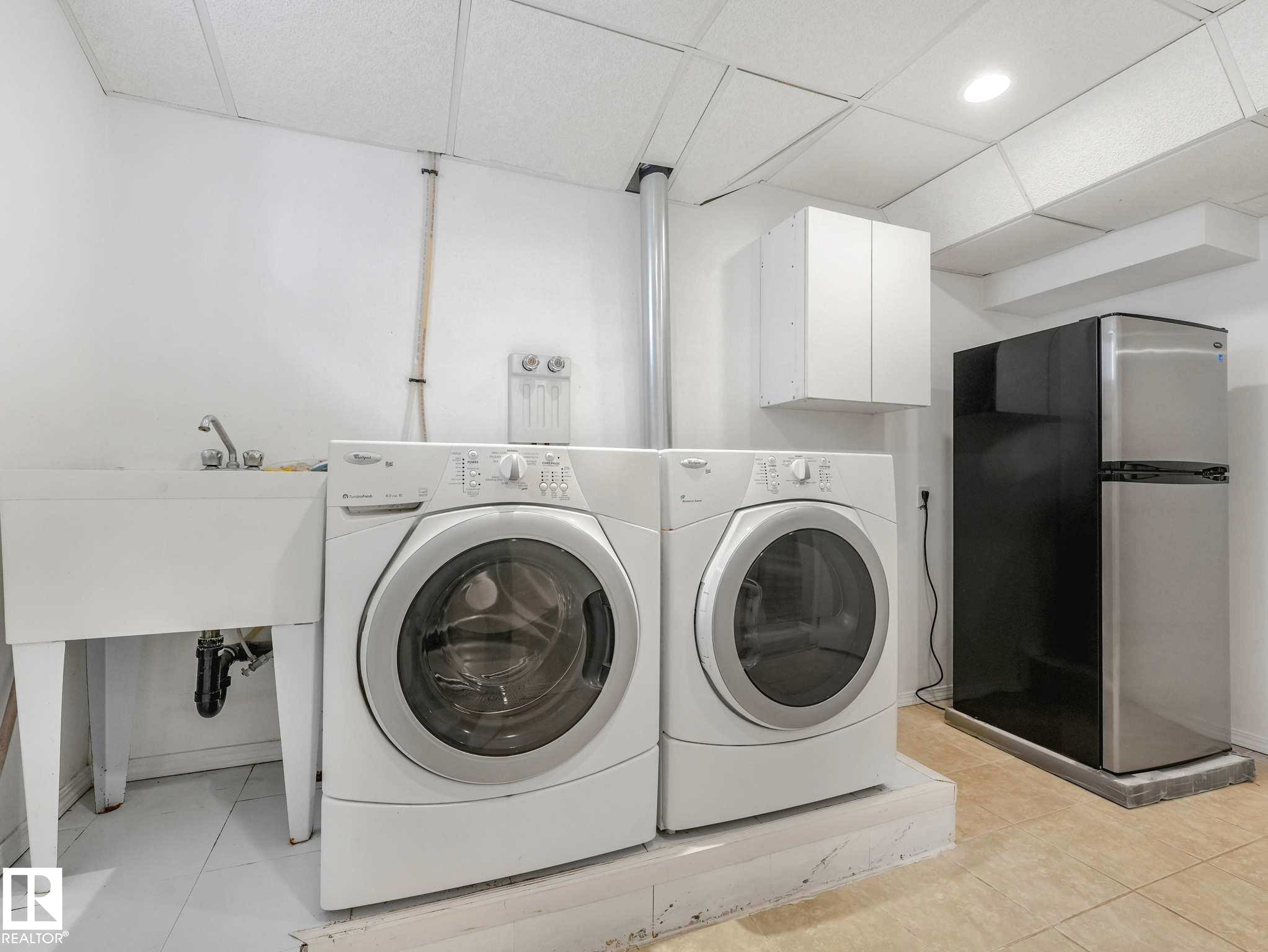 Laundry area featuring a utility sink, mounted wall cabinetry, and tile flooring - 15916 88B Avenue Nw, Edmonton, AB